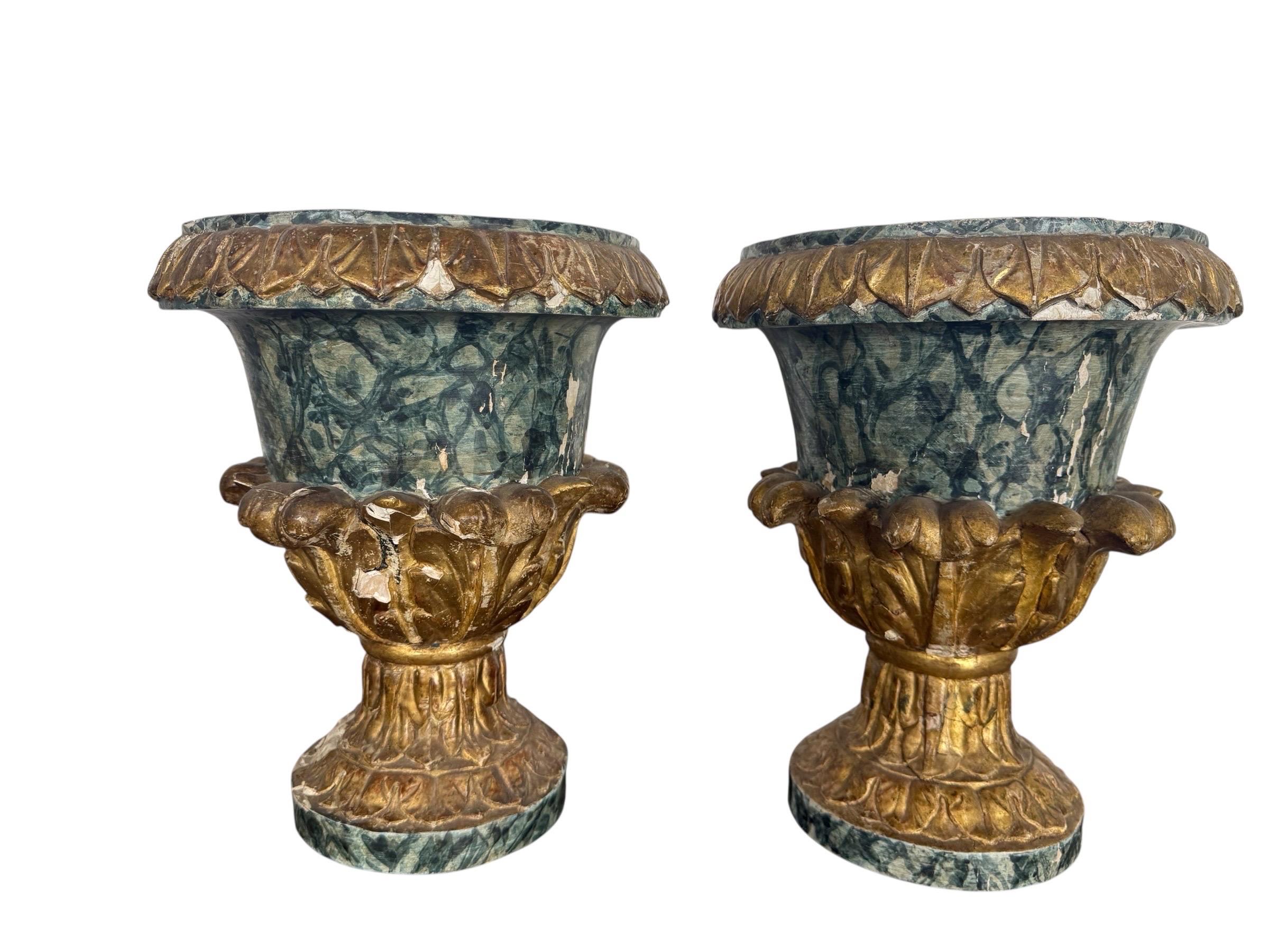 Una bella coppia di urne in legno intagliato del XIX secolo, splendidamente decorate con una sorprendente finitura policroma. I corpi presentano una ricca vernice finto-marmo in tonalità di verde intenso, accentuata da dettagli foliati dorati lungo