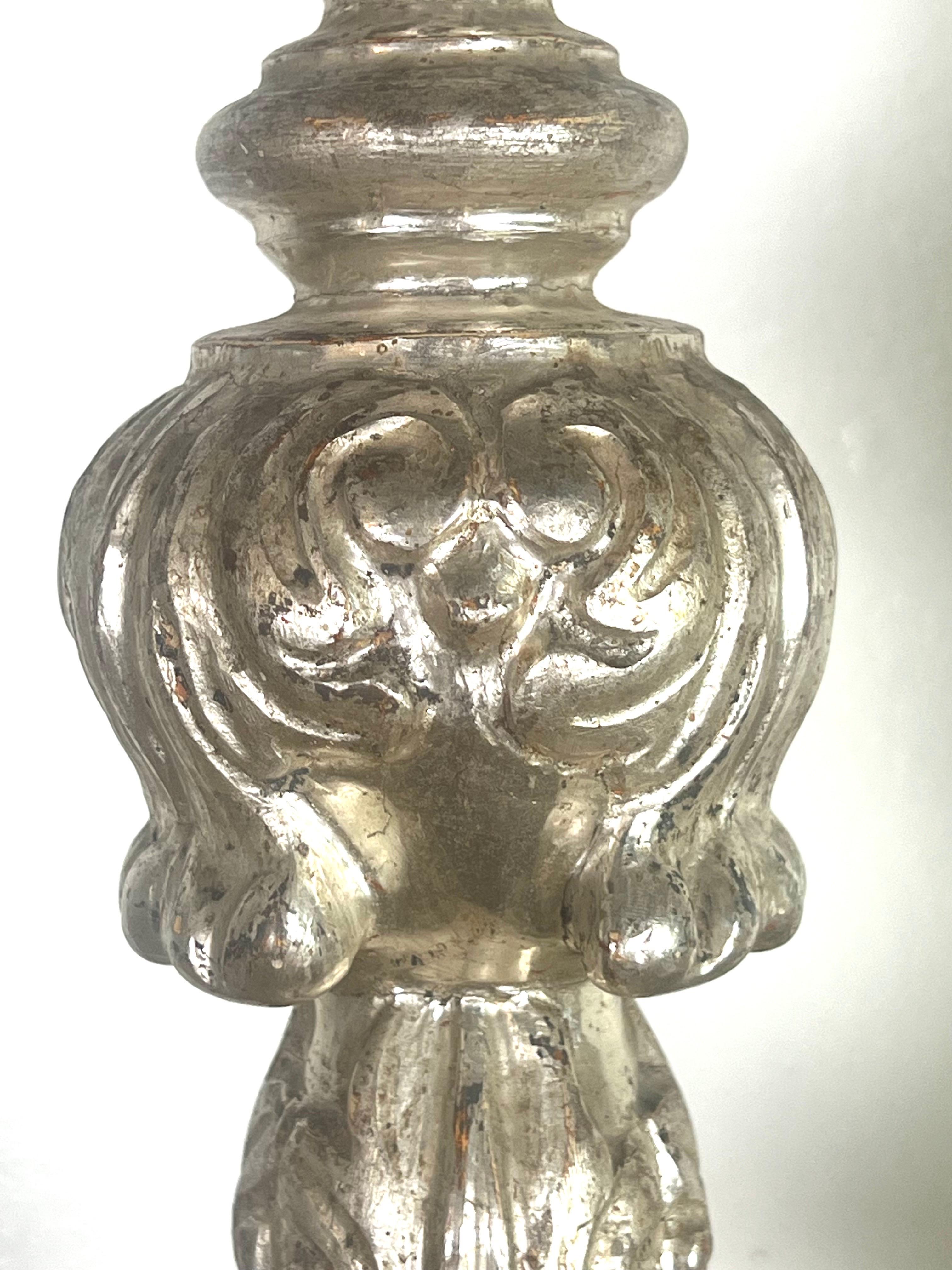Paire de chandeliers en bois argenté et doré du 19e siècle reposant sur une base tripode.  Les chandeliers sont ornés de bobèches en fer forgé et de prickets en métal.