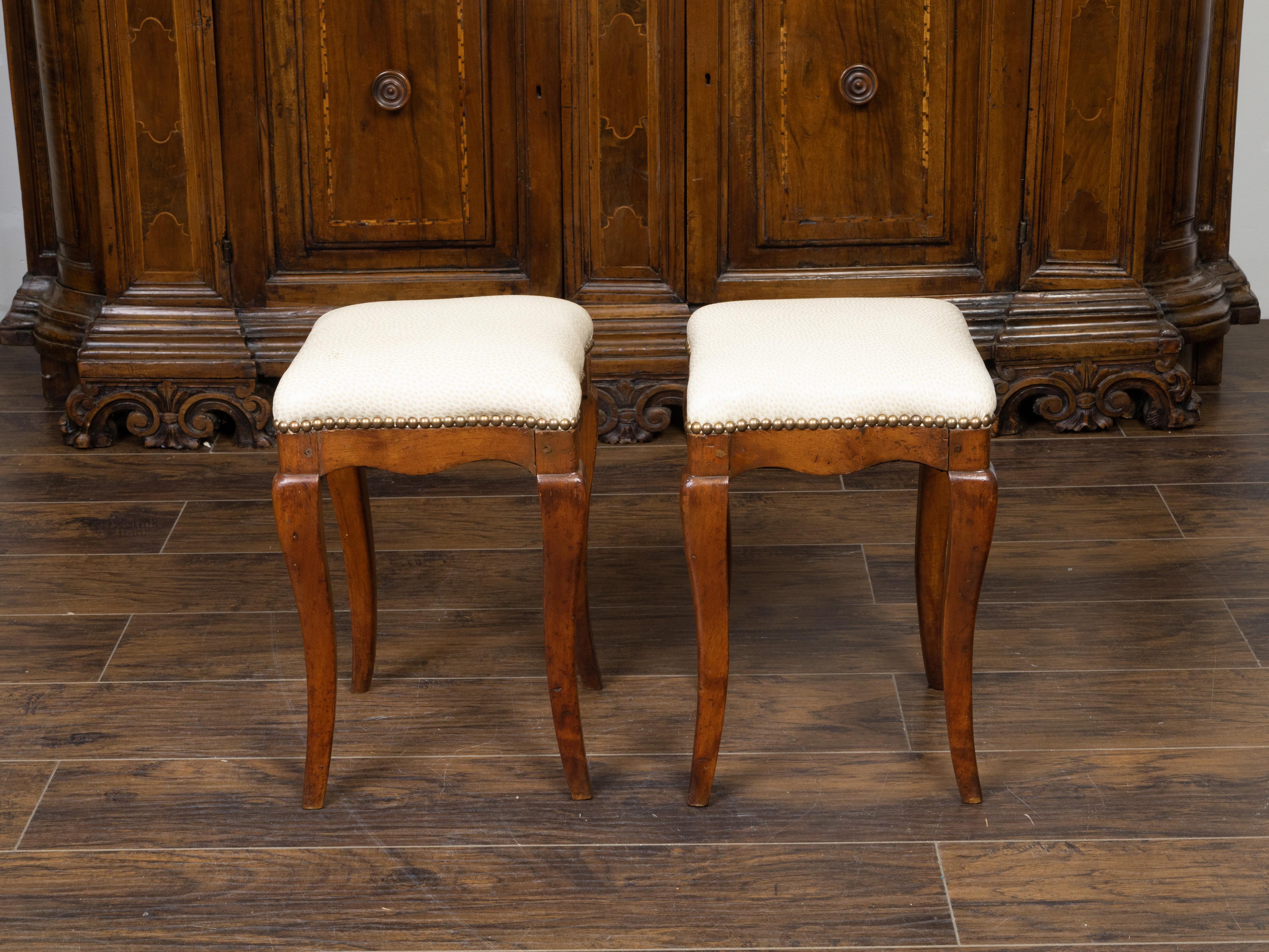 A pair of Italian walnut stools from the 19th century, with cabriole legs and new upholstery. Created in Italy during the 19th century, each of this pair of walnut stools features a square top newly reupholstered with a textured neutral toned fabric