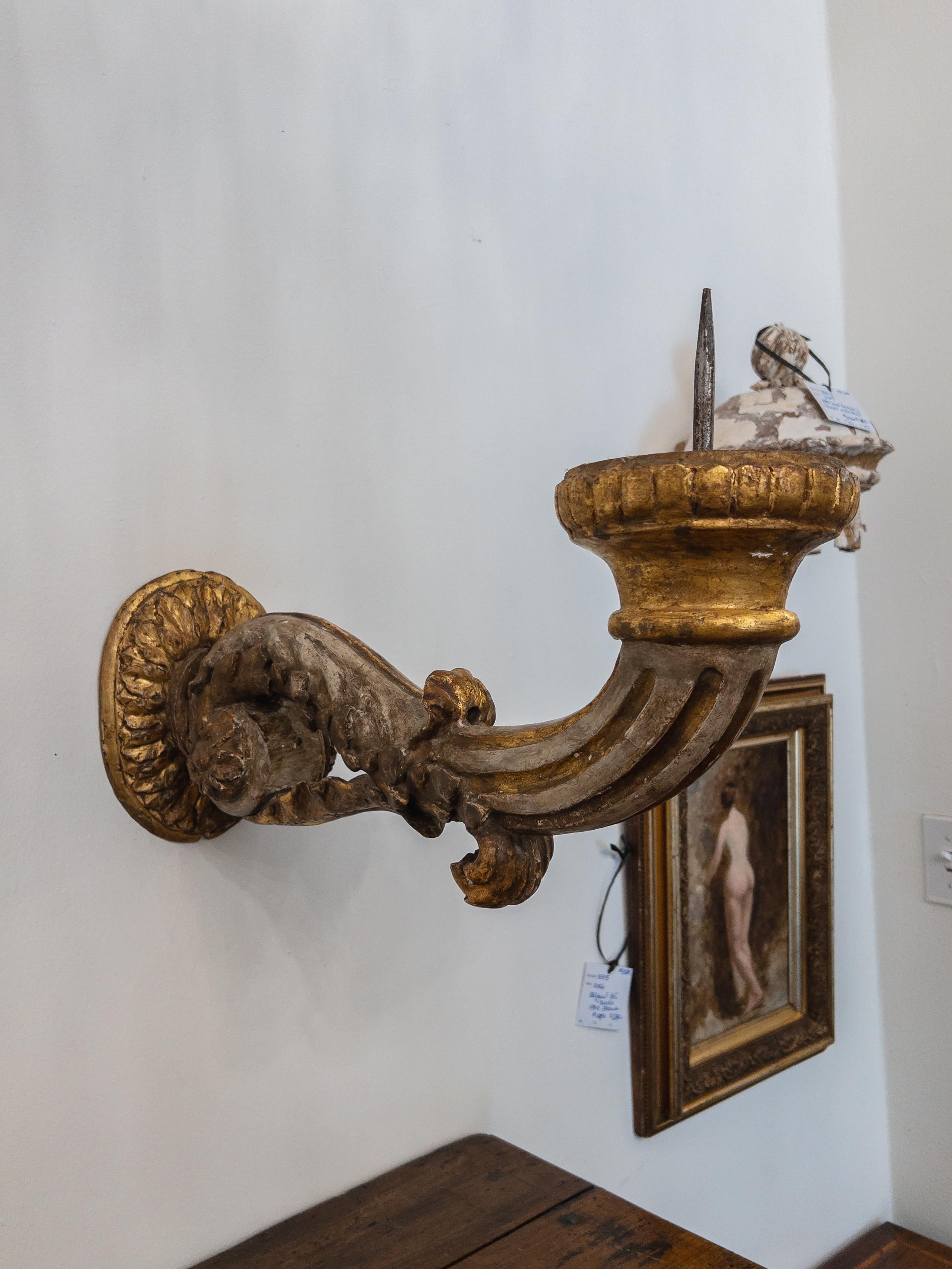 A pair of 19th-century Italian wood-carved pricket sconces are exquisite and antique wall-mounted candleholders. These sconces are crafted from wood, and their design showcases intricate carvings, displaying the artistic talent of Italian