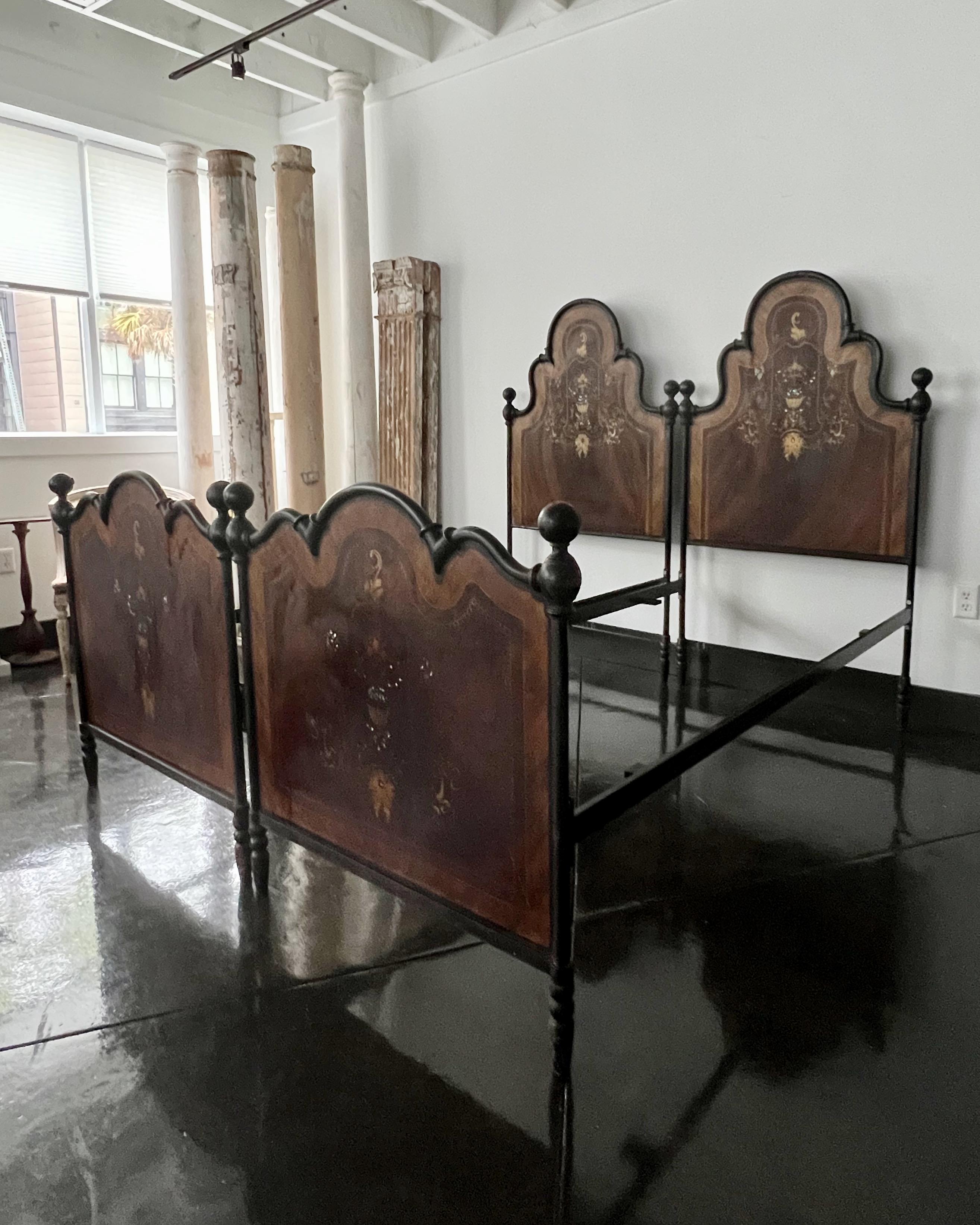 Handsome pair of Italian wrought iron/tole bed frames with hand-painted imitation wood effect with magnificent detailed floral desings and mother of pearls accents. 
Italy, 19th c.
Beds come apart for transportation.
Measures:
Beds wide 37