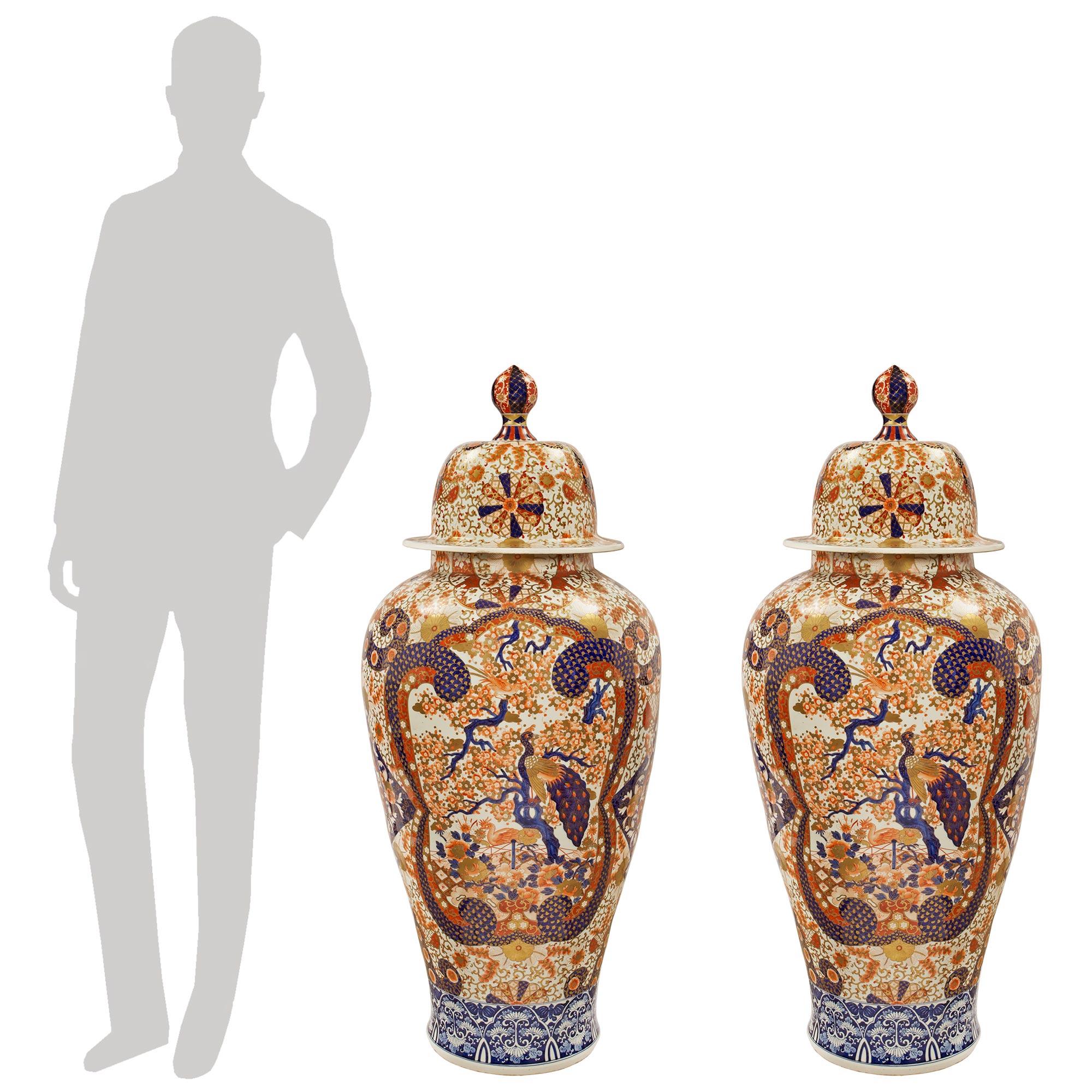 An important and large pair of mid 19th century Japanese Imari porcelain baluster shaped urns. The pair is richly detailed throughout with a foliate landscape décor and a large Peacock. The similarly decorated lids end with a top finial.

  