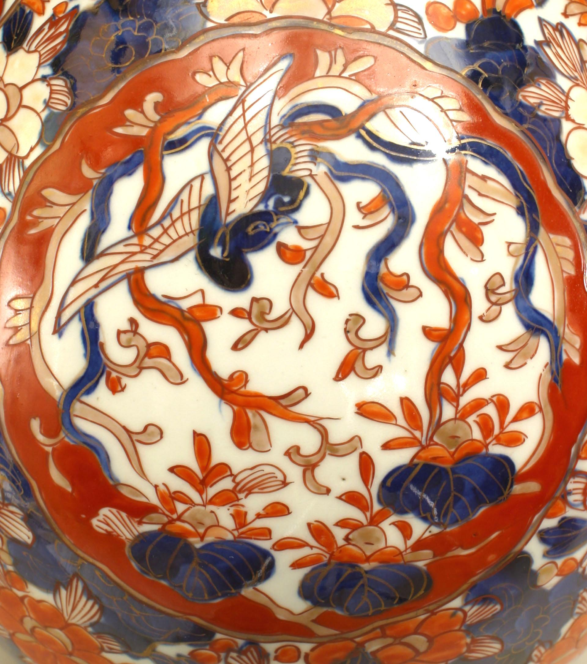 Paire de vases en porcelaine japonaise Imari du 19e siècle, à col élancé, représentant des motifs floraux et d'oiseaux dans des tons de rouge et de cobalt.