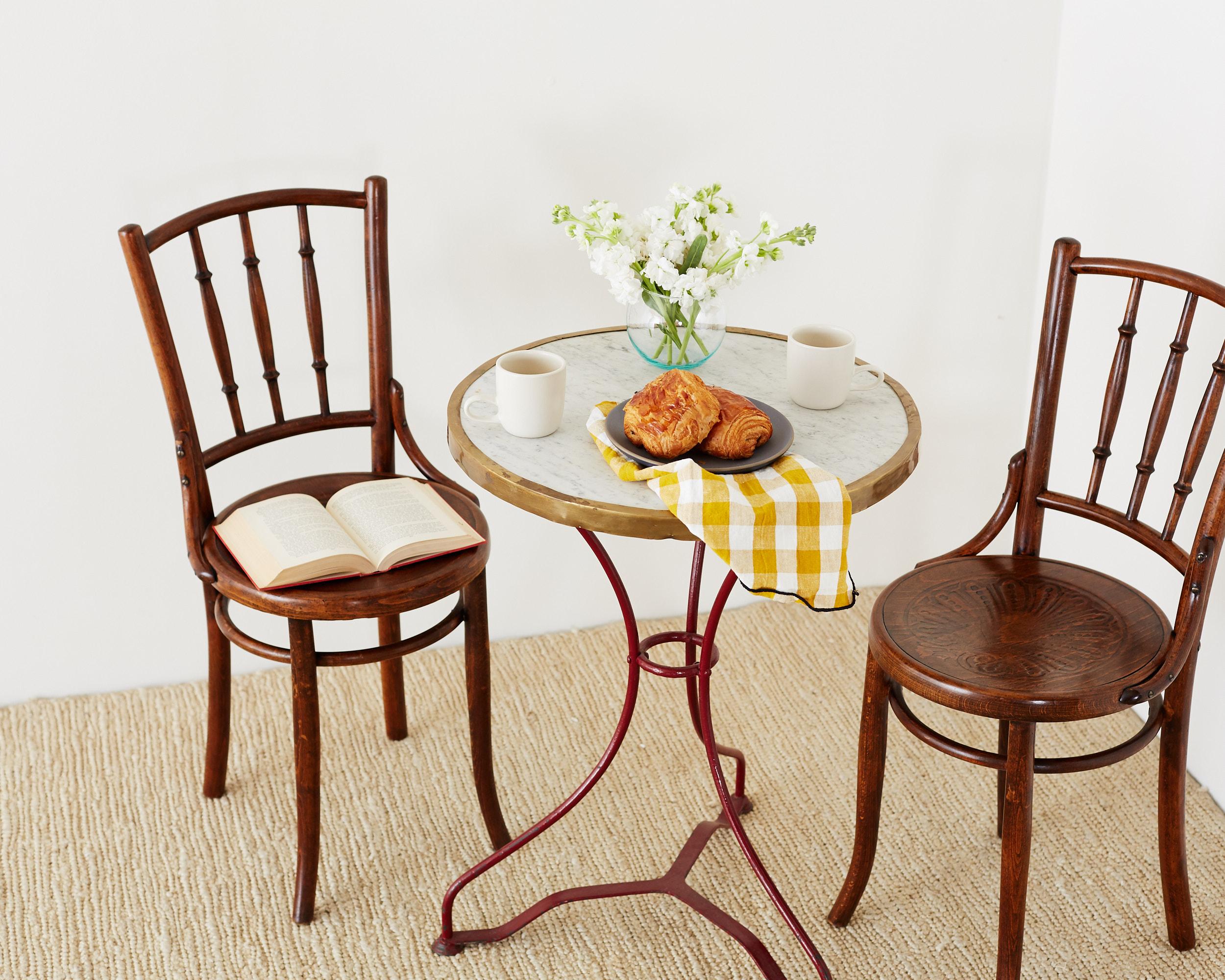 Charming pair of 19th century Viennese bentwood cafe chairs produced by Mundus for Jacob and Josep Kohn. Classic design bistro style chair, but with a spindle back and a decorative palmette or peacock design on the seat. Both chairs having the