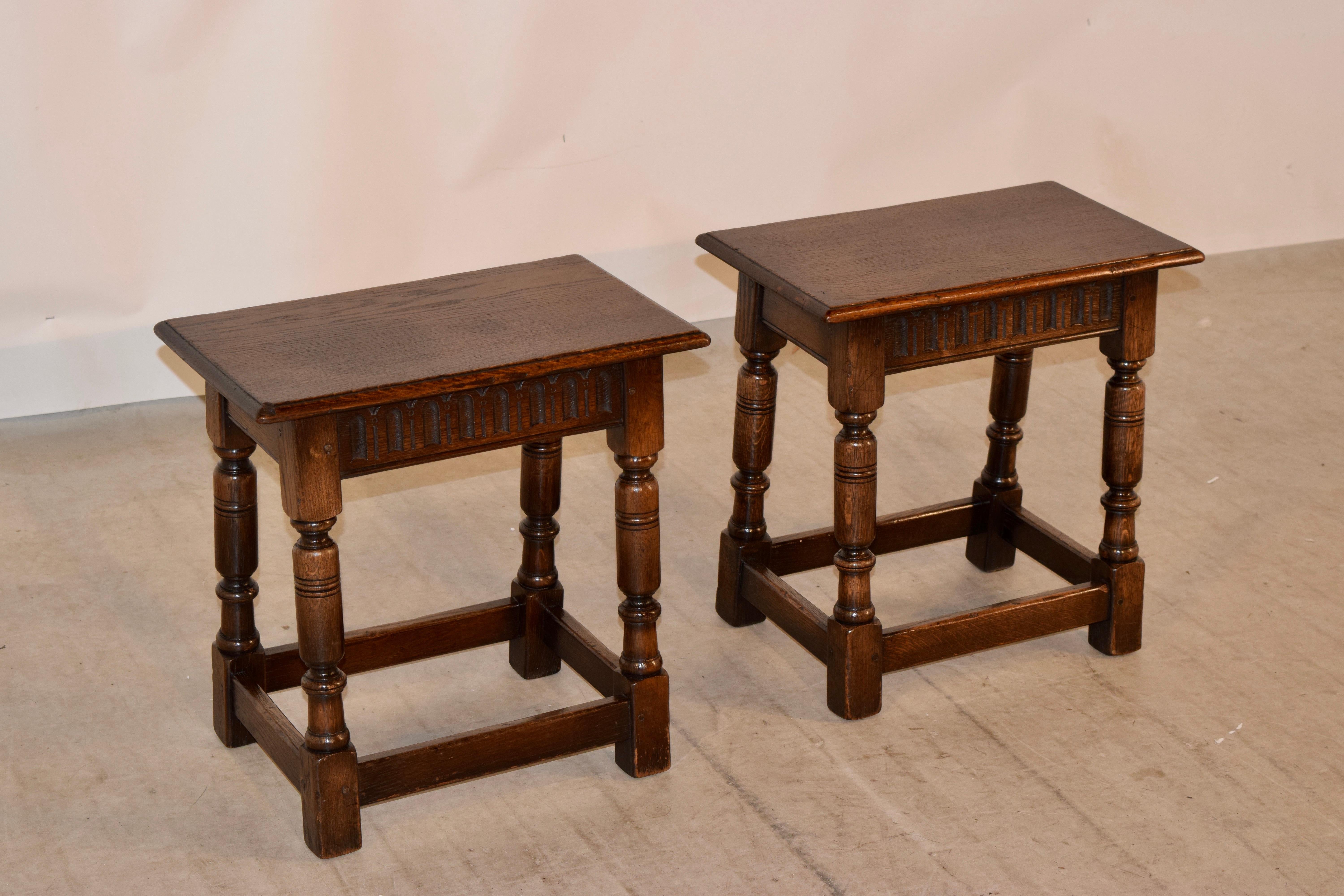 Pair of 19th century English oak joint stools with beveled edges around the seats, following down to carved simple aprons with fluted decoration and wonderfully hand turned legs joined by simple stretchers. Pegged construction.