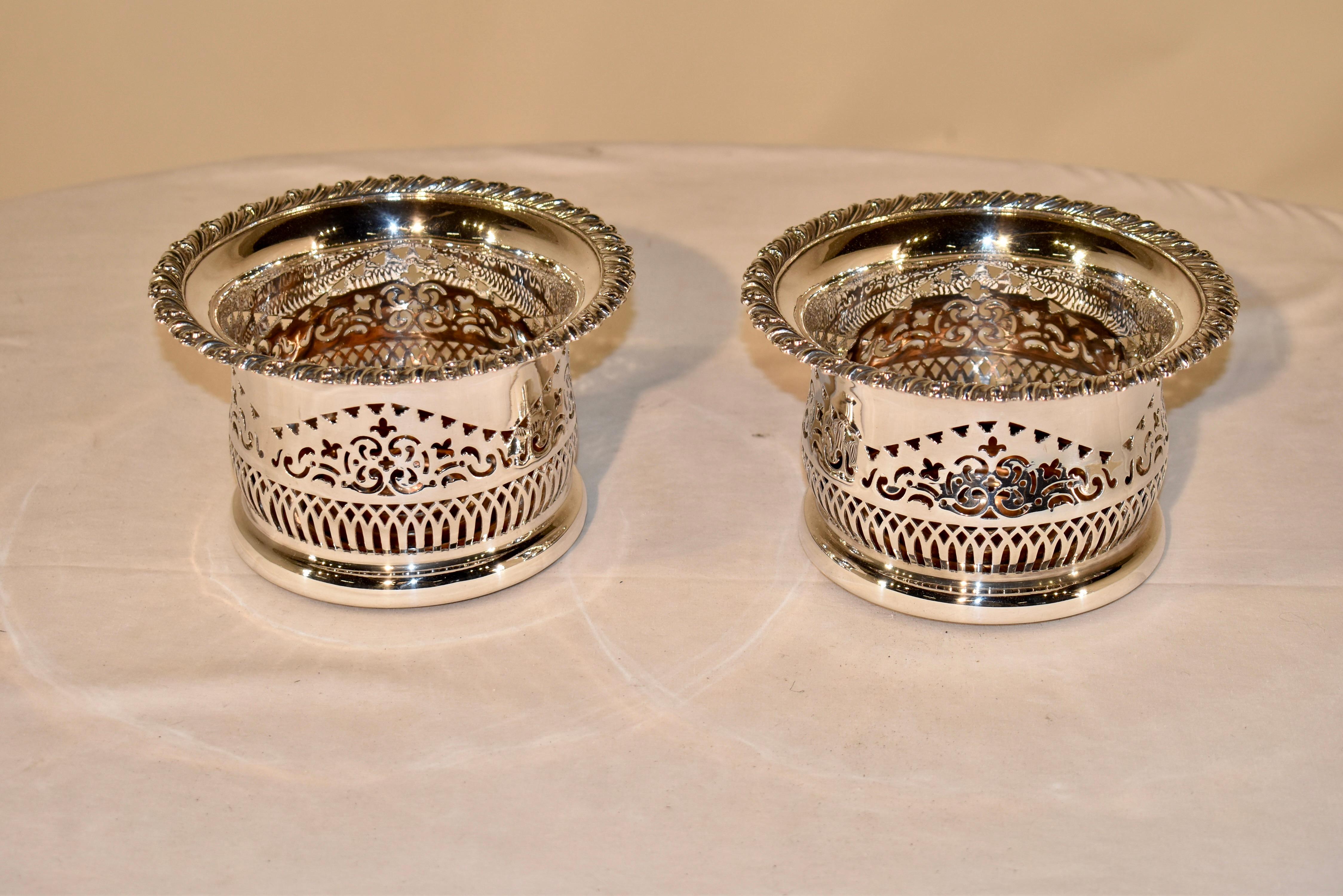 Pair of lovely late 19th century large bottle coasters from England. The pair is silver plated and have oak bases. They have scrolled borders, and are pierced decorated on the sides. These would be a stunning addition to any table or sideboard.