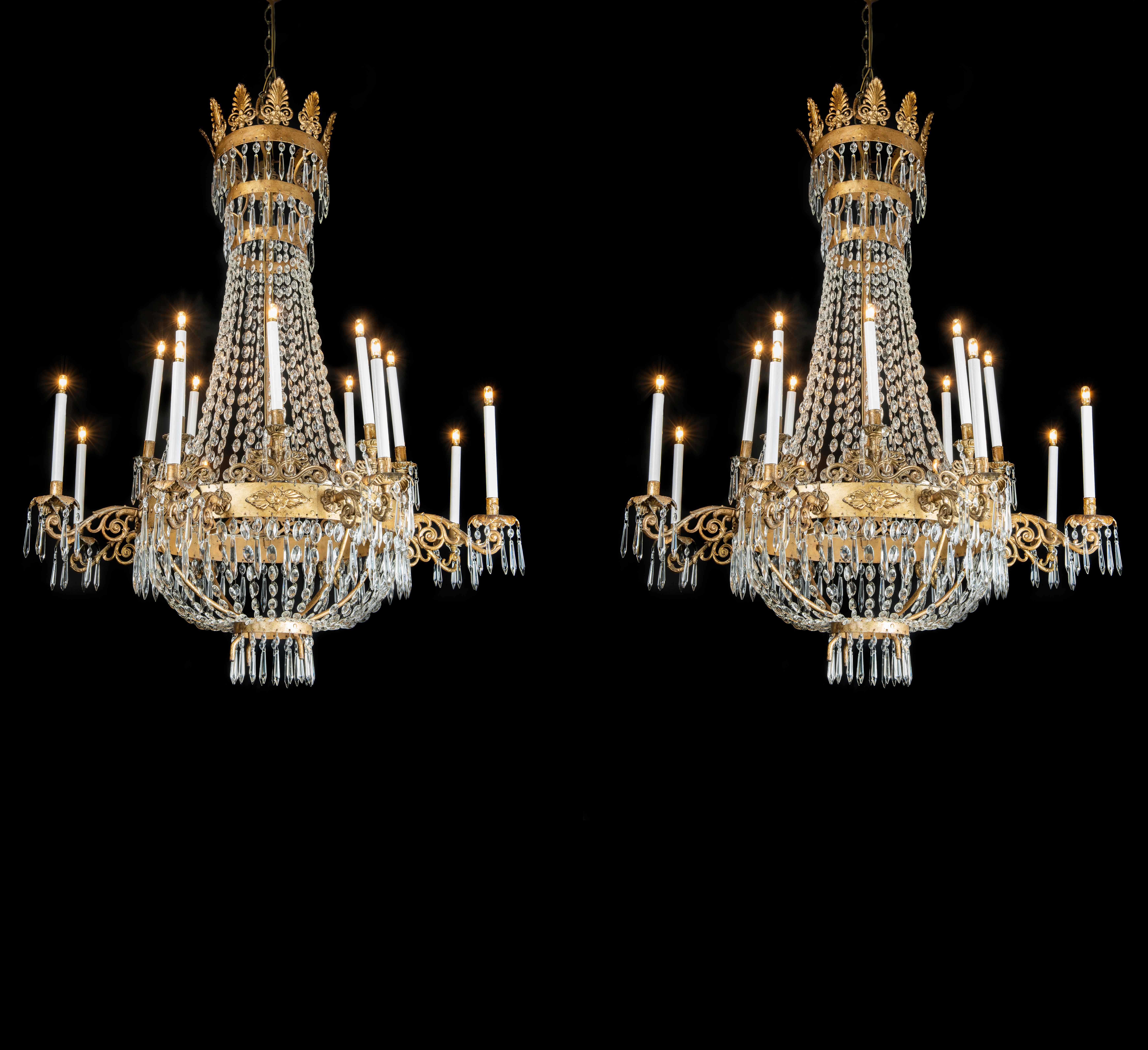 A large scale pair of Italian Empire period crystal and mecca gilt iron chandeliers,  an hand-made circular structure featuring two tiers supporting sixteen arms, dating back to early 19th century of Italian origin, coming from a Piedmontese private
