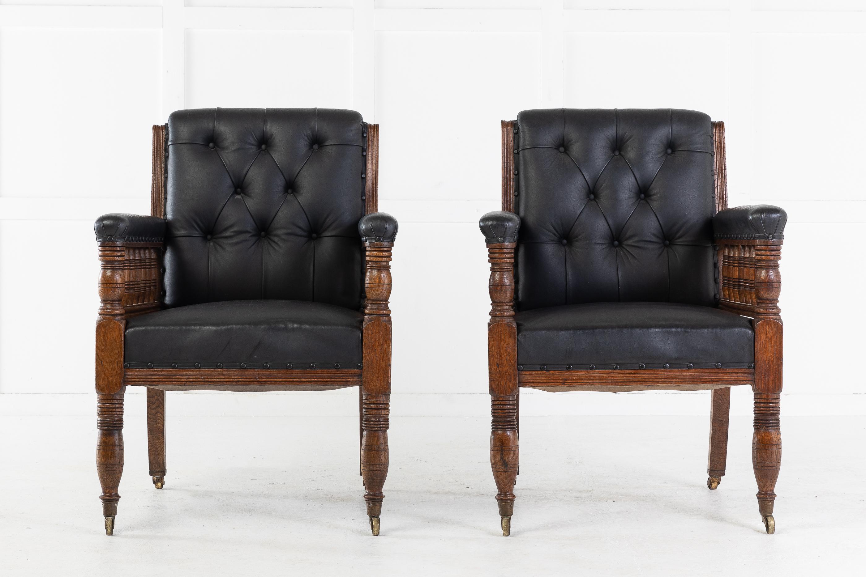 Pair of large scale, oversized 19th century oak, button backed, armchairs with nicely turned spindle, decorated arms. Upholstered in quality blue hide. Turned front legs and outswept back legs, terminating in brass castors.
      