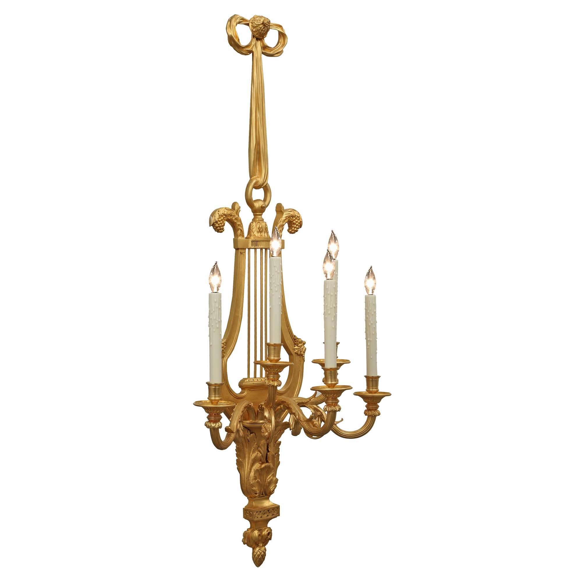 An exquisite pair of 19th century Louis XVI st. large scale ormolu sconces. Each remarkable sconce has five 's' scrolled arms decorated with acanthus leaves. The lyre shaped pierced backplate has a bottom acorn finial below a running wave border.