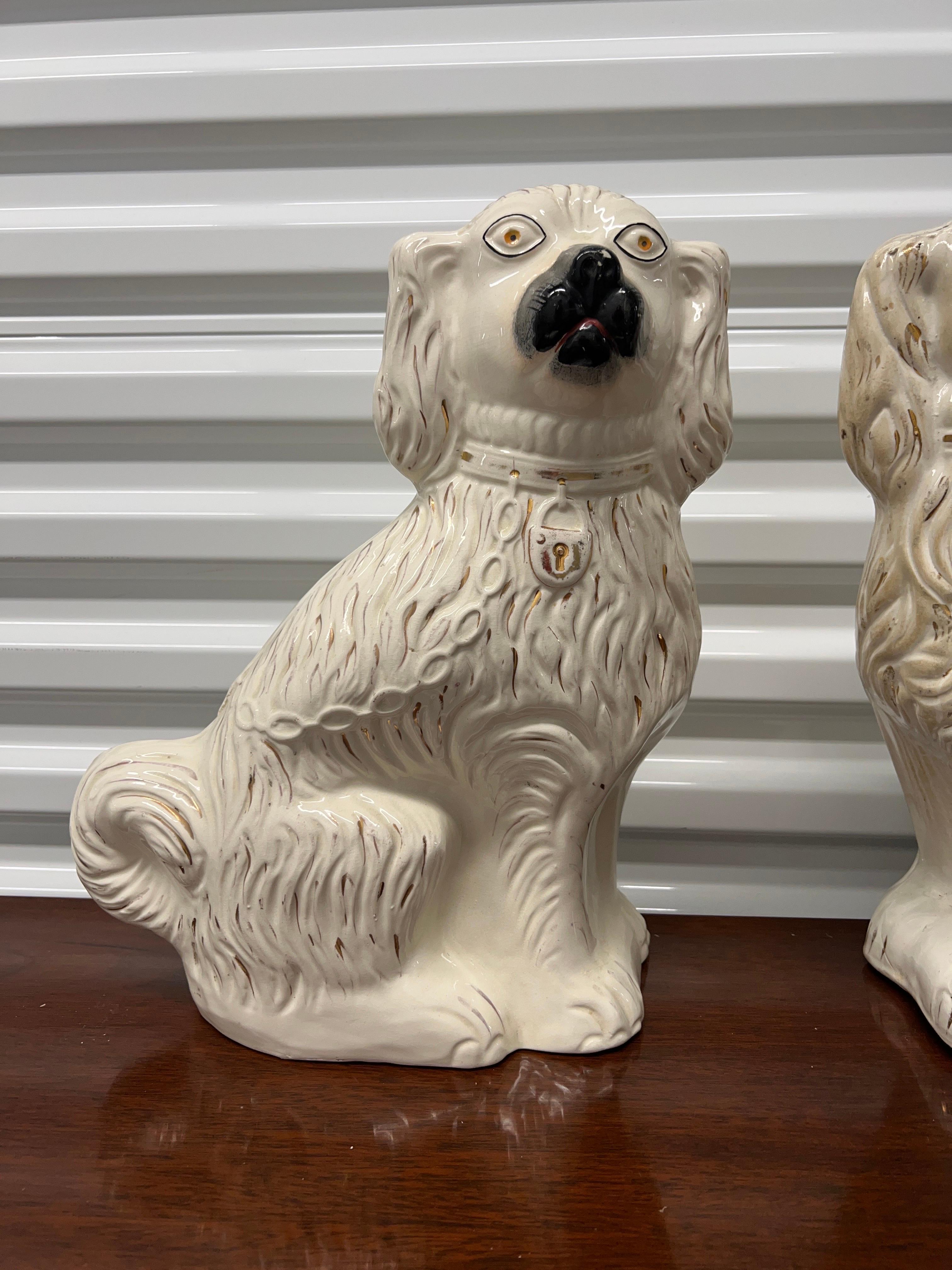 English, 19th century.

A pair of English Staffordshire spaniels in white glaze, black nose and key lock chain to body. 15.25