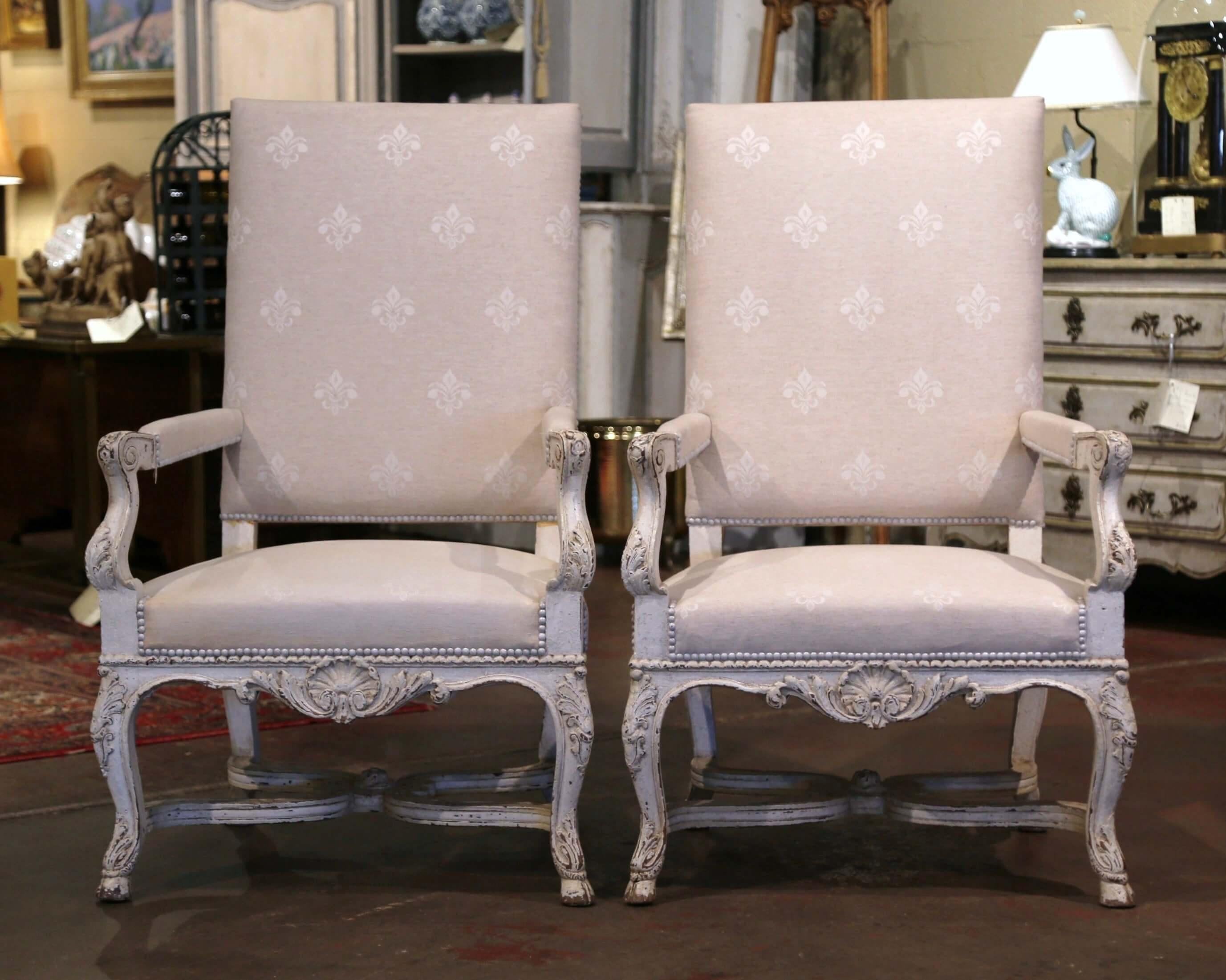 These elegant antique armchairs were crafted in France, circa 1870. Each large fauteuil stands on cabriole legs ending with hoof feet over an intricate curved bottom stretcher embellished with a middle carved floral medallion; it is further