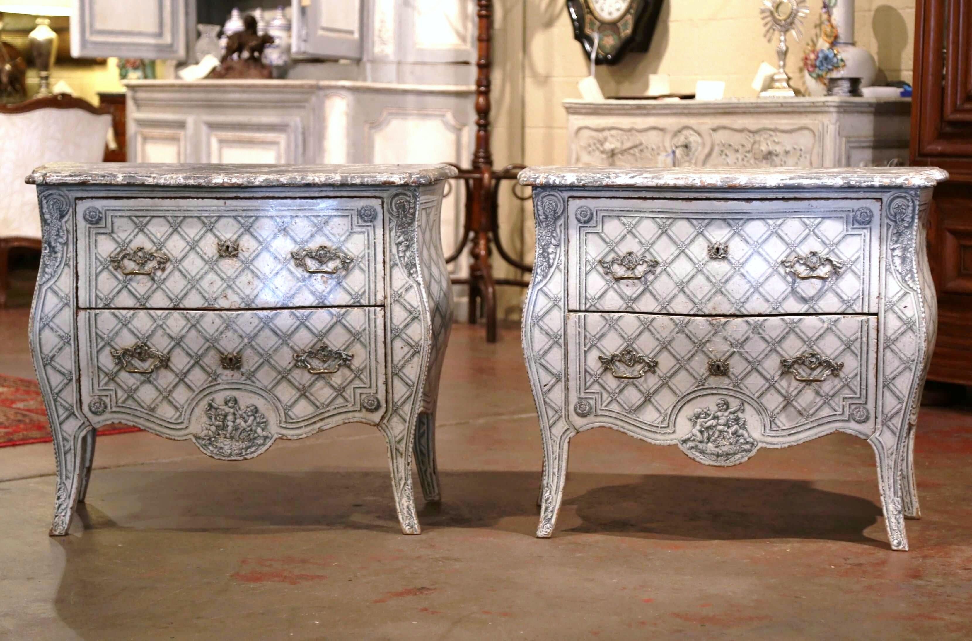 Decorate a master suite with this elegant pair of antique painted chests of drawers. Crafted in France, circa 1890, the commodes with bombe front and sides, stand on cabriole legs over a scalloped apron. Each cabinet features detailed painted