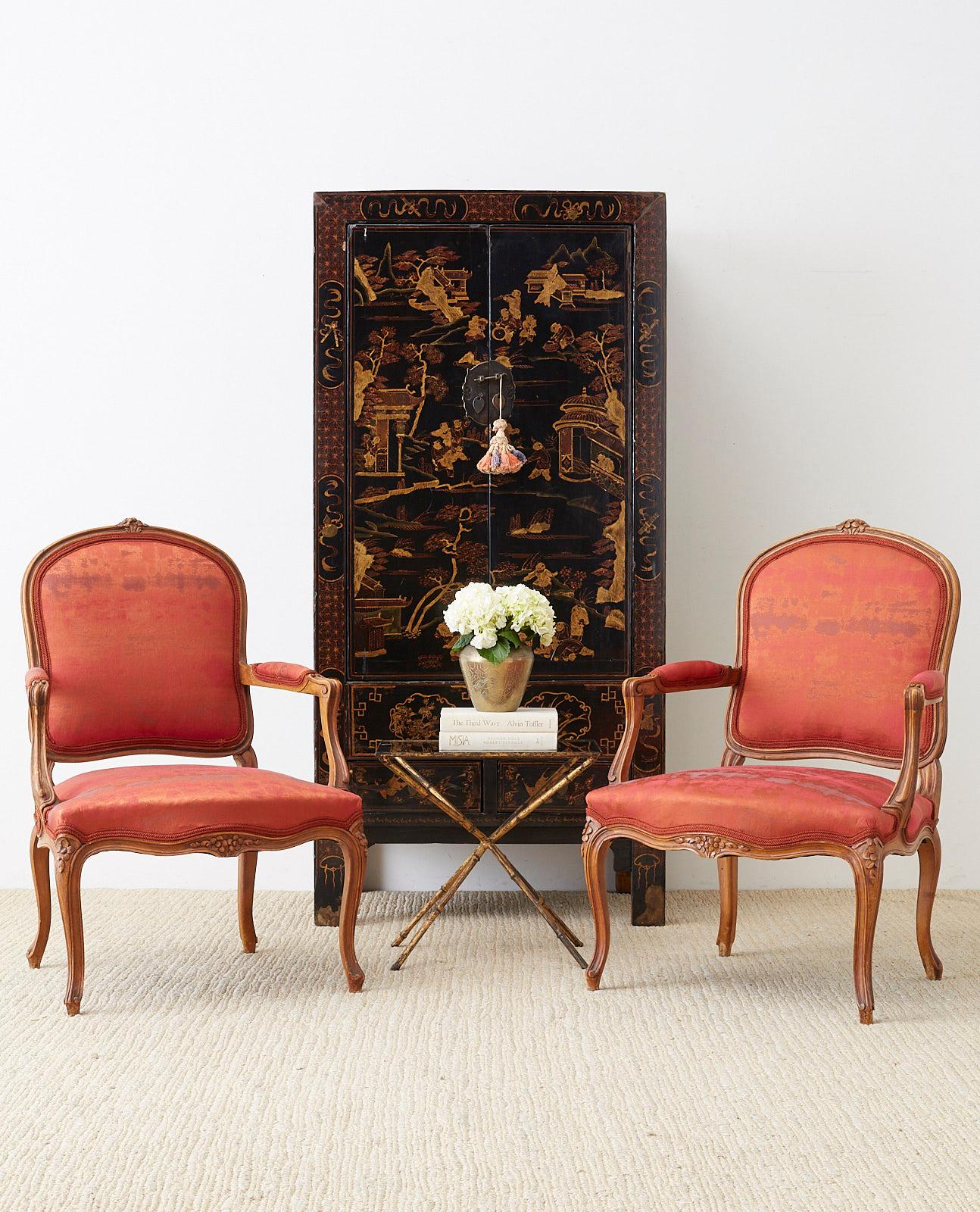 Fabulous pair of French carved walnut fauteuils made in the Louis XV style featuring a Chinese silk style upholstery with an antique look. Newly upholstered with a rich fabric that displays orange and red hues. The frame features a shaped back with