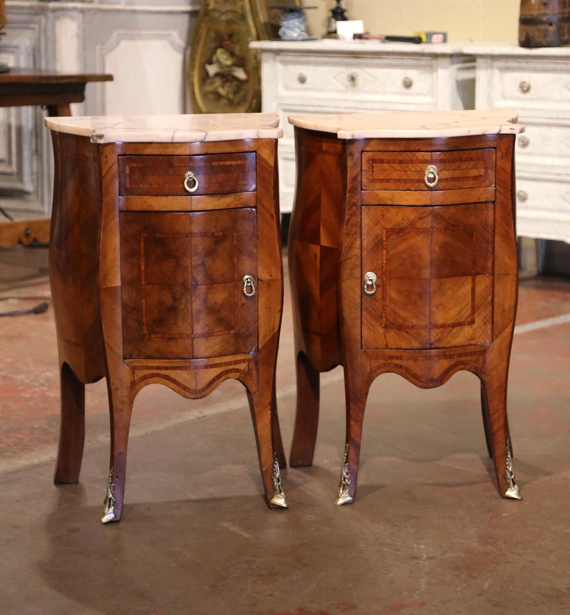 These elegant antique bedside tables were created in France, circa 1890. Bombe on all three sides with marquetry inlay and veneer bands throughout, the fruitwood chests stand on cabriole legs ending with decorative bronze sabot feet over a scalloped