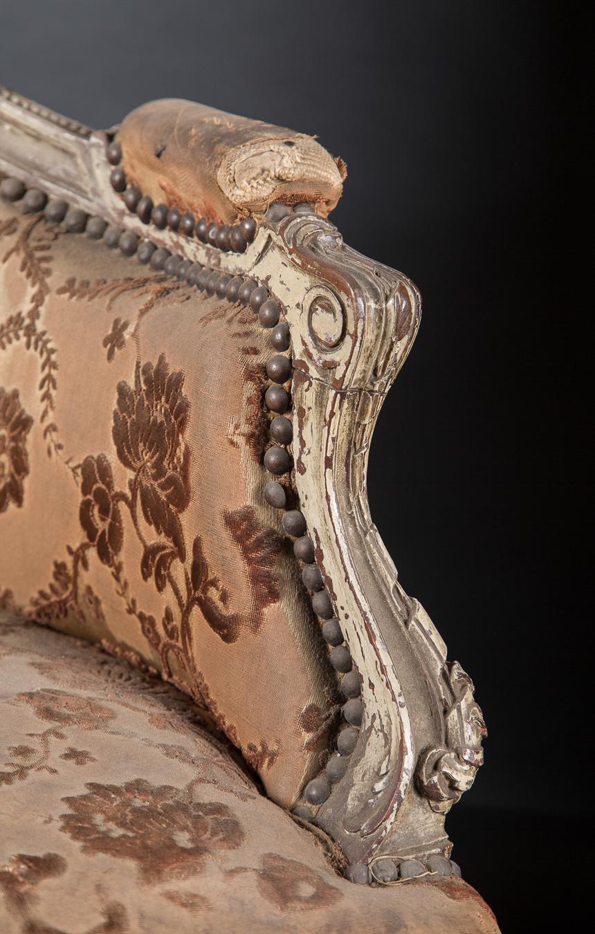 This beautiful pair of Louis XV bergeres are painted and stunningly carved. Dating back to the 19th century, the French antique armchairs feature details in plenty; note the carvings on the arms, the cabriole legs with scroll feet, the pattern work
