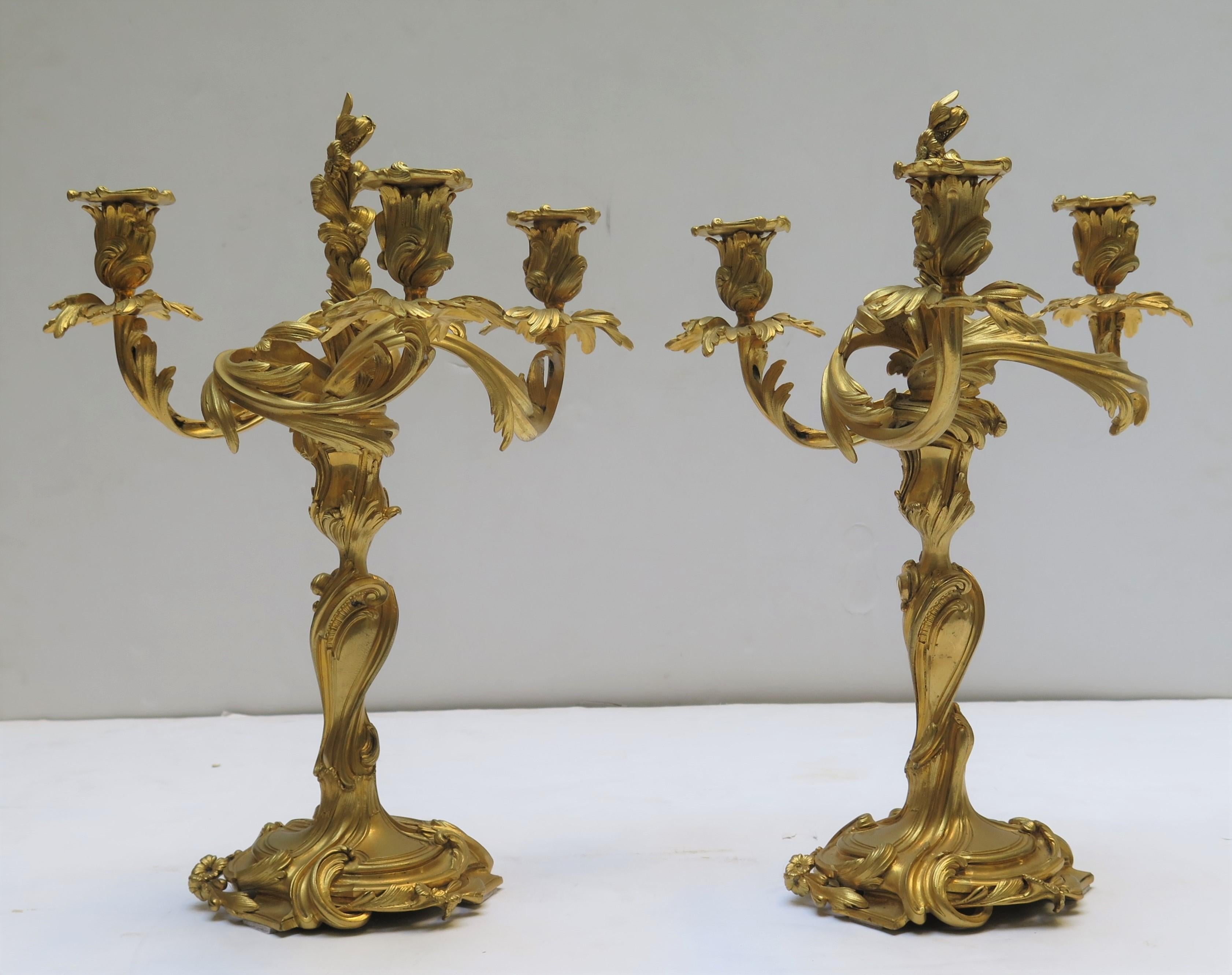 A pair of Louis XV style gilded bronze three-armed antique foliate candelabra of French origin.
Acanthus leaf scrolling arms with leaf bobeches.