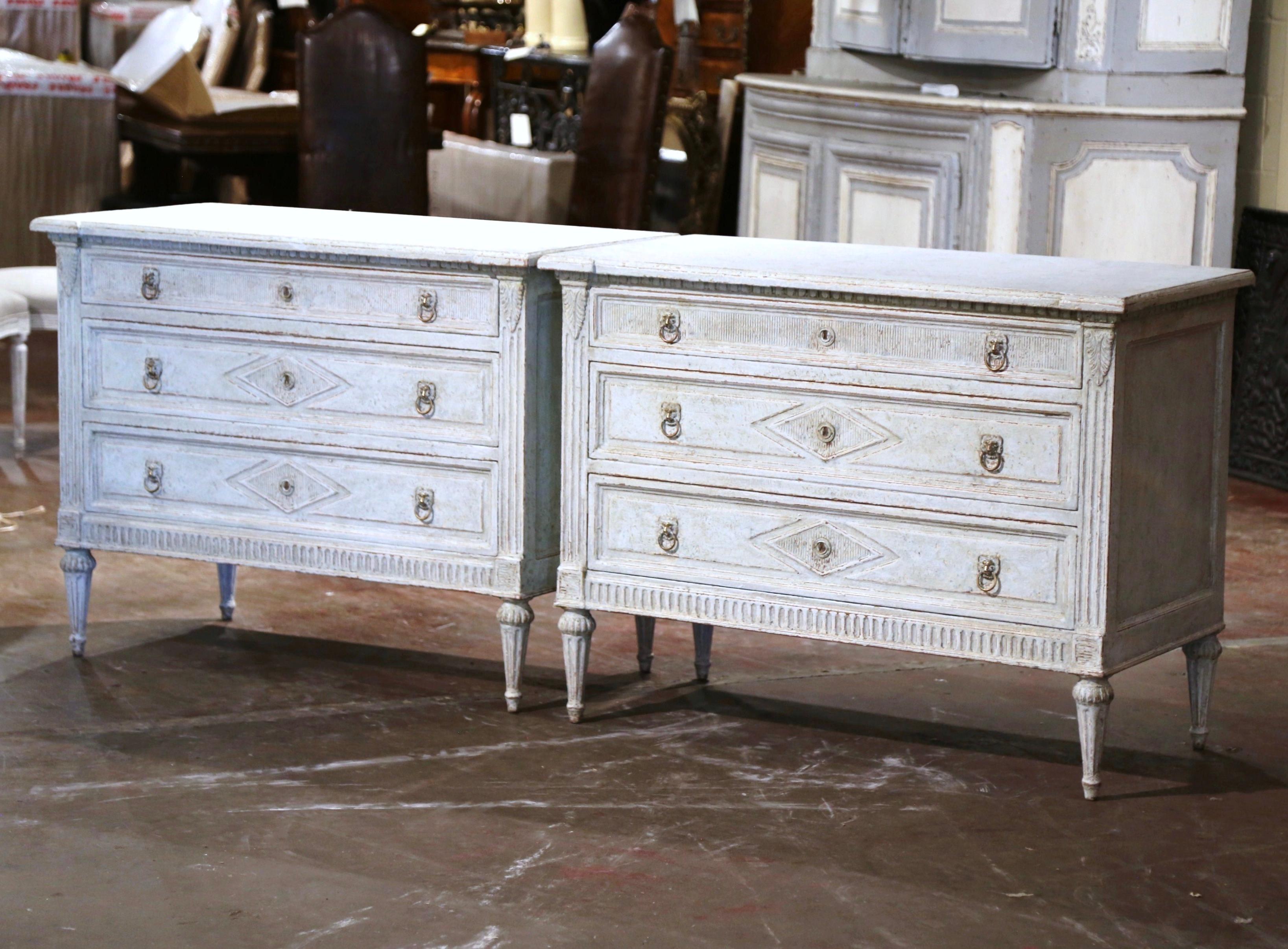 Use this elegant pair of antique painted chests of drawers on either side of a mantel, on in an entry way. Crafted in France circa 1860, each cabinet sits on tapered and fluted feet decorated with floral rosette medallion at the shoulder, over a