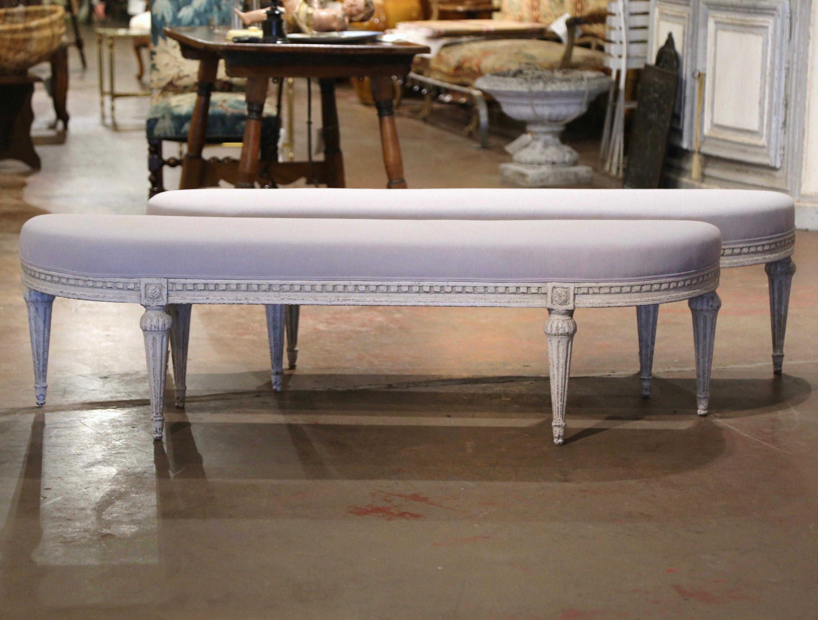 Complete your entryway or living room with this pair of antique painted benches. Crafted in France, circa 1890, each bench stands on six tapered and fluted legs decorated with floral medallions rosettes at the shoulder. The seating features rounded