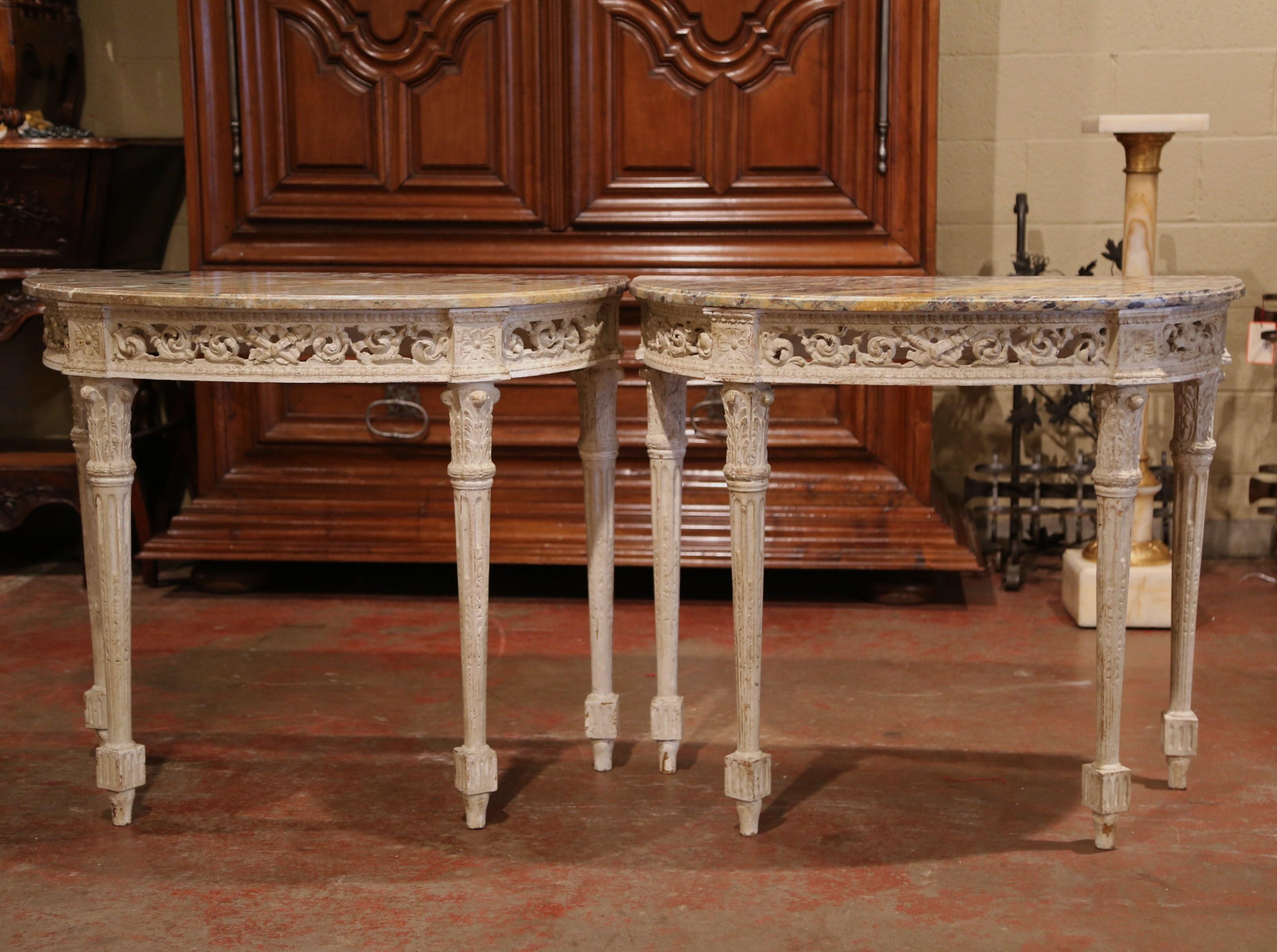 Decorate an entryway with this sophisticated pair of antique consoles tables. Crafted in Southern France circa 1880 and shaped as half moon, each demilune table stands on four tapered legs decorated with acanthus leaves at the shoulders; the half