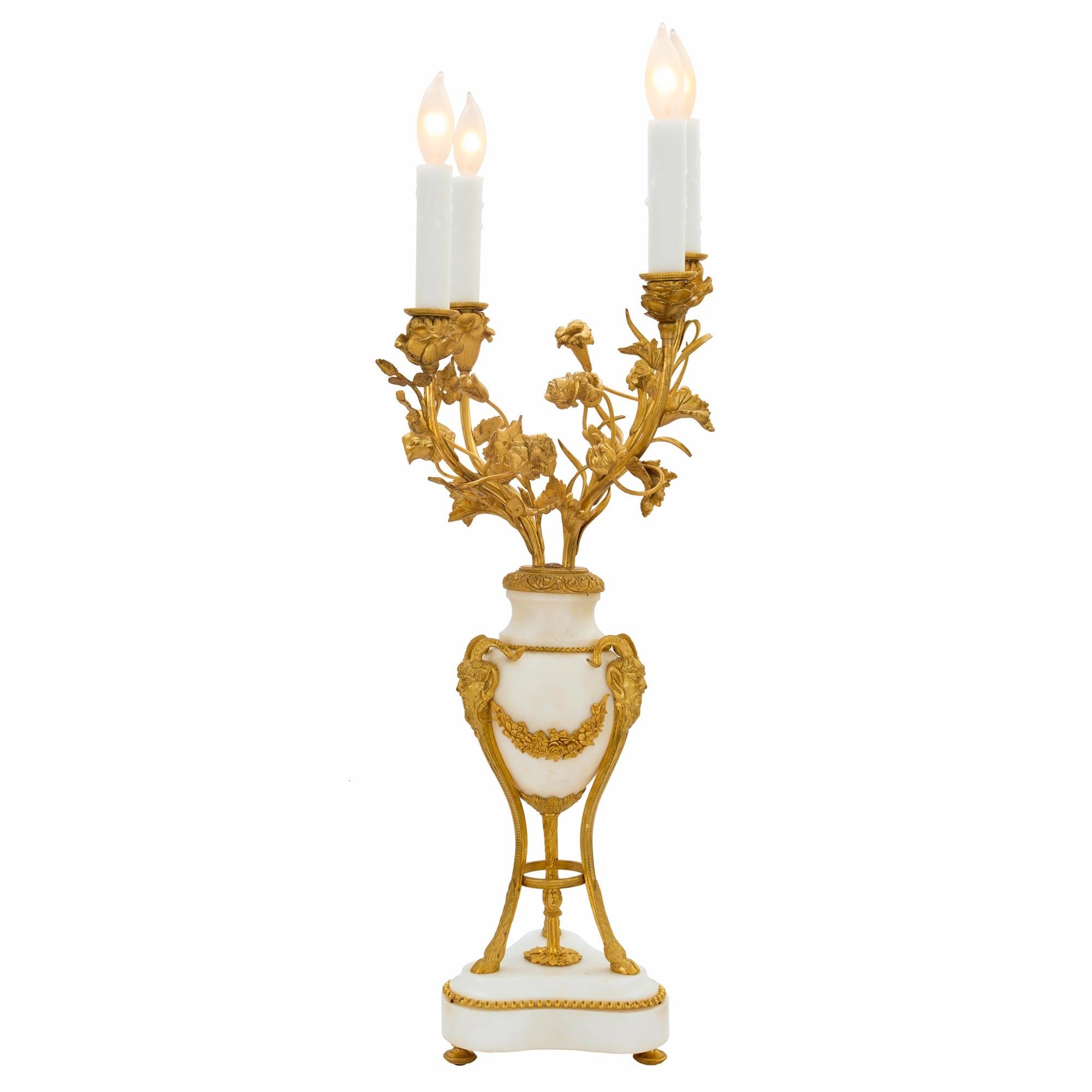 A handsome pair of French mid 19th century Louis XVI st. white Carrara marble and ormolu electrified candelabras. Each are raised by a Carrara marble base with canted corners on ormolu topie supports and ormolu beaded border. Three ormolu supports