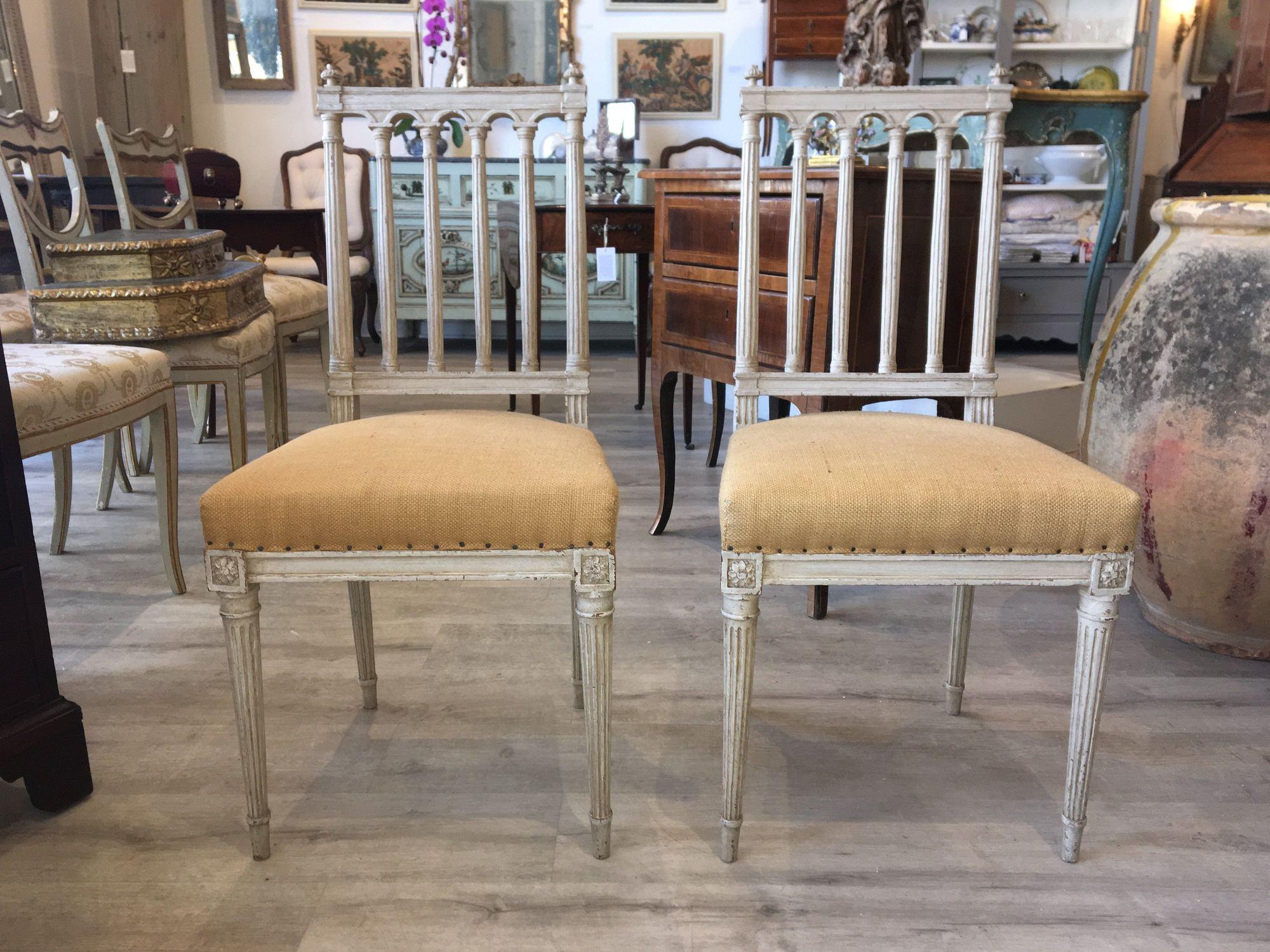 Pair of 19th century Louis XVI style French side chairs, white painted with charming fluted column backrest over a burlap-upholstered seat resting on tapered fluted legs.