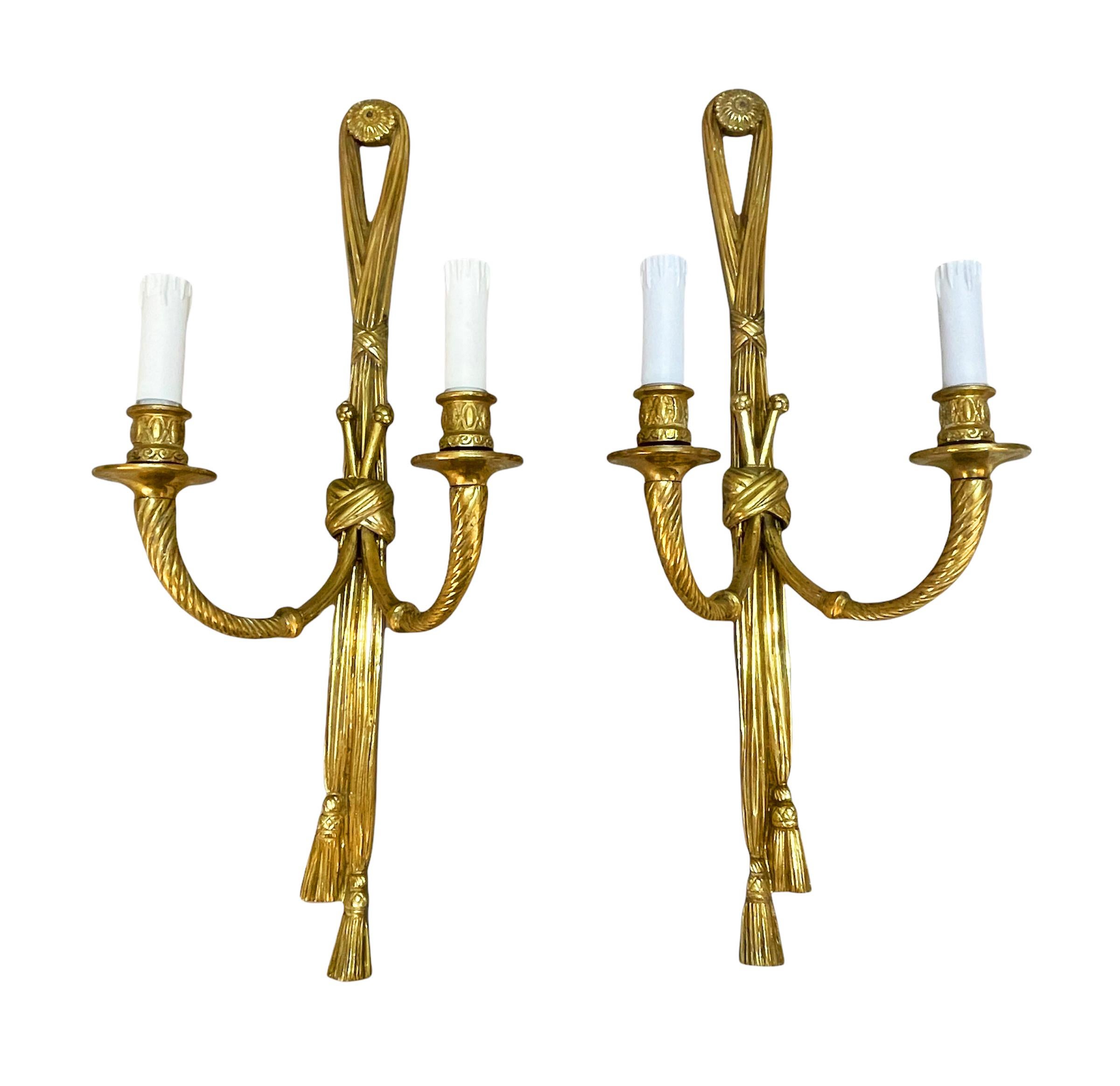 Wunderschönes Paar vergoldeter Bronzewandleuchter in Form von geknoteten Bändern, die zwei Kerzenarme halten. Diese erstaunlichen Sets wurden im 19. Jahrhundert in Frankreich hergestellt.

Beide bemerkenswerten Stücke enden in Quasten, die über