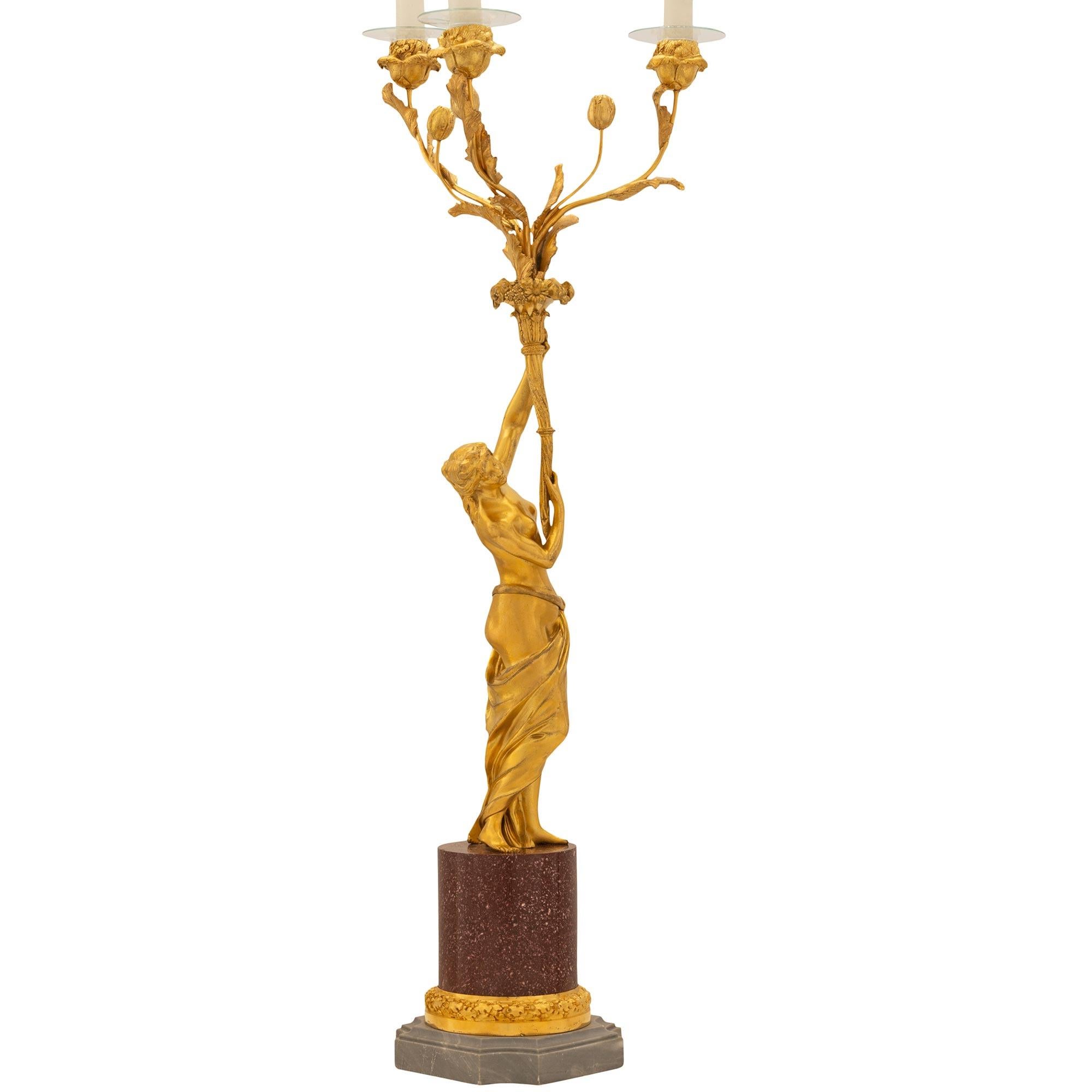 A stunning and extremely high quality true pair of French 19th century Louis XVI st. ormolu, Bleu Turquin marble, and Porphyry candelabras. Each candelabra is raised by a square Bleu Turquin marble base with concave corners and an elegant and most