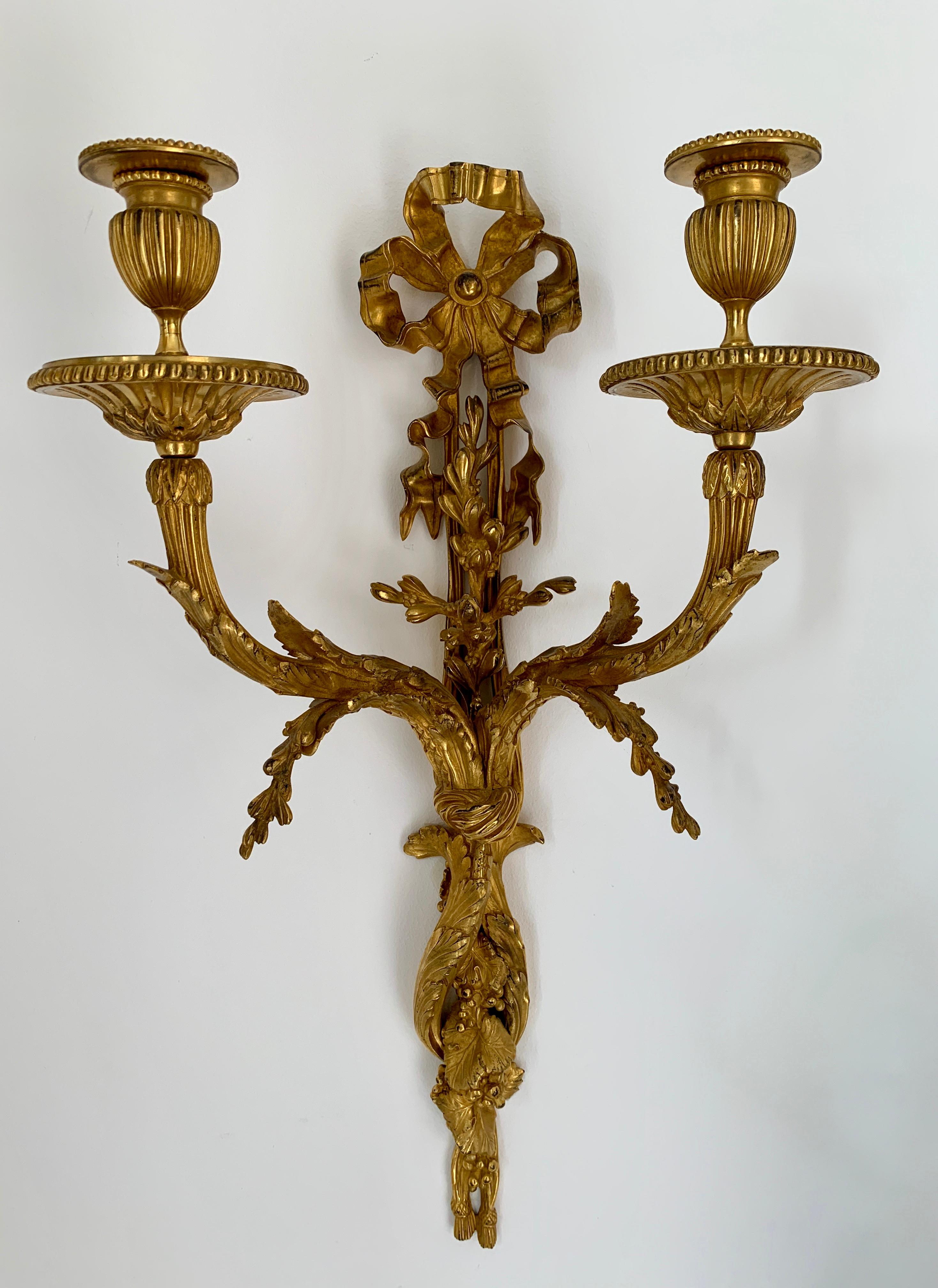 A very high quality and rare pair of French 19th century Louis XVI style gilt-bronze twin-branch wall appliques. The superb sconces display sensationally chased grapes and vines below two S scrolled reeded arms. Each arm is seamlessly tied together