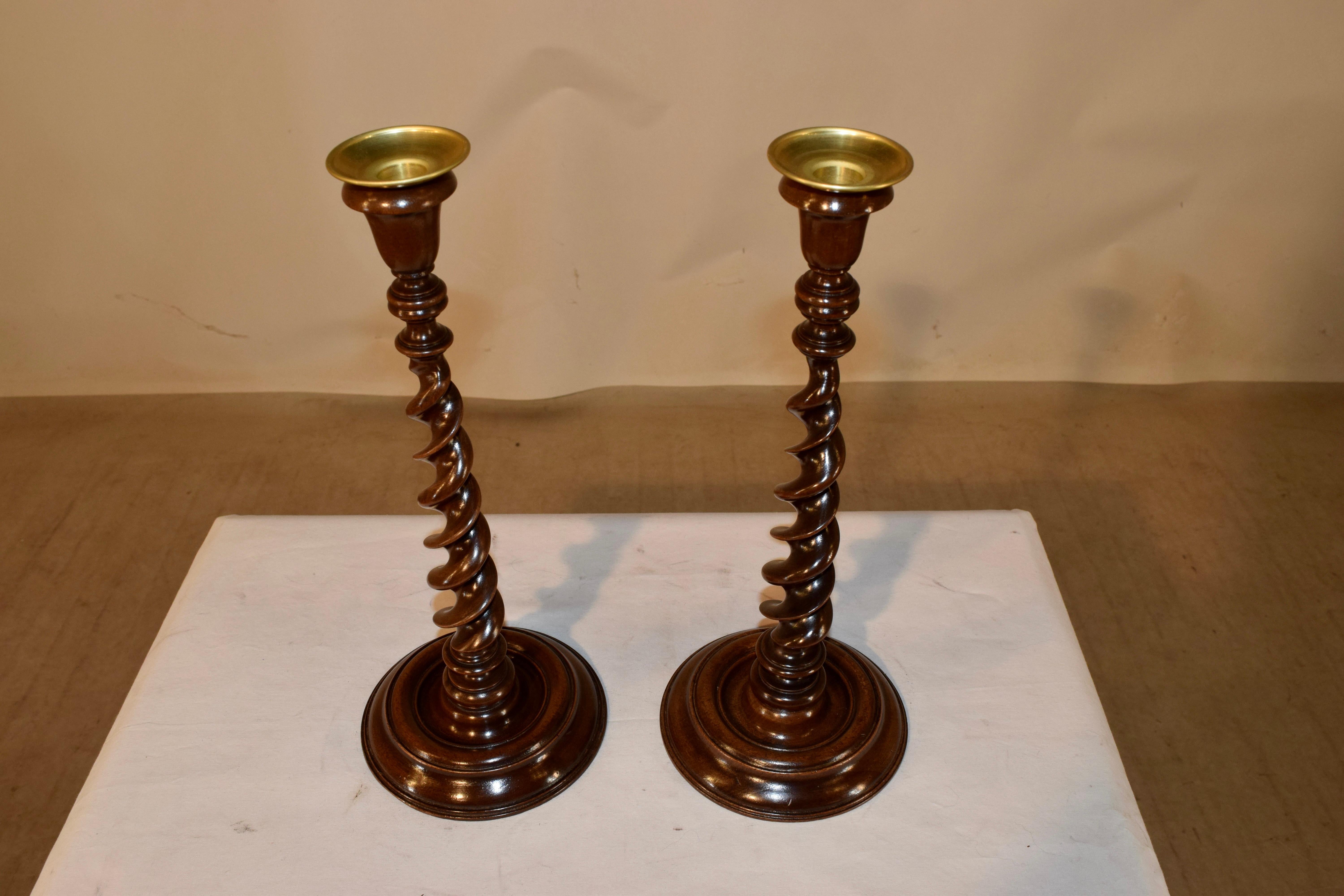 Pair of 19th century English ribbon twist candlesticks made from mahogany. The bobeches and candle cups are hand cast brass supported on finely hand-turned ribbon barley twist stems over turned bases. Elegant form.