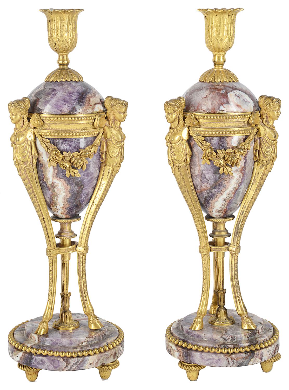 A very good quality pair of early 19th century marble and gilded ormolu candle sticks, each with winged female monopodia mounts, foliate swag decoration, tripod supports terminating in hoof feet and marble bases.