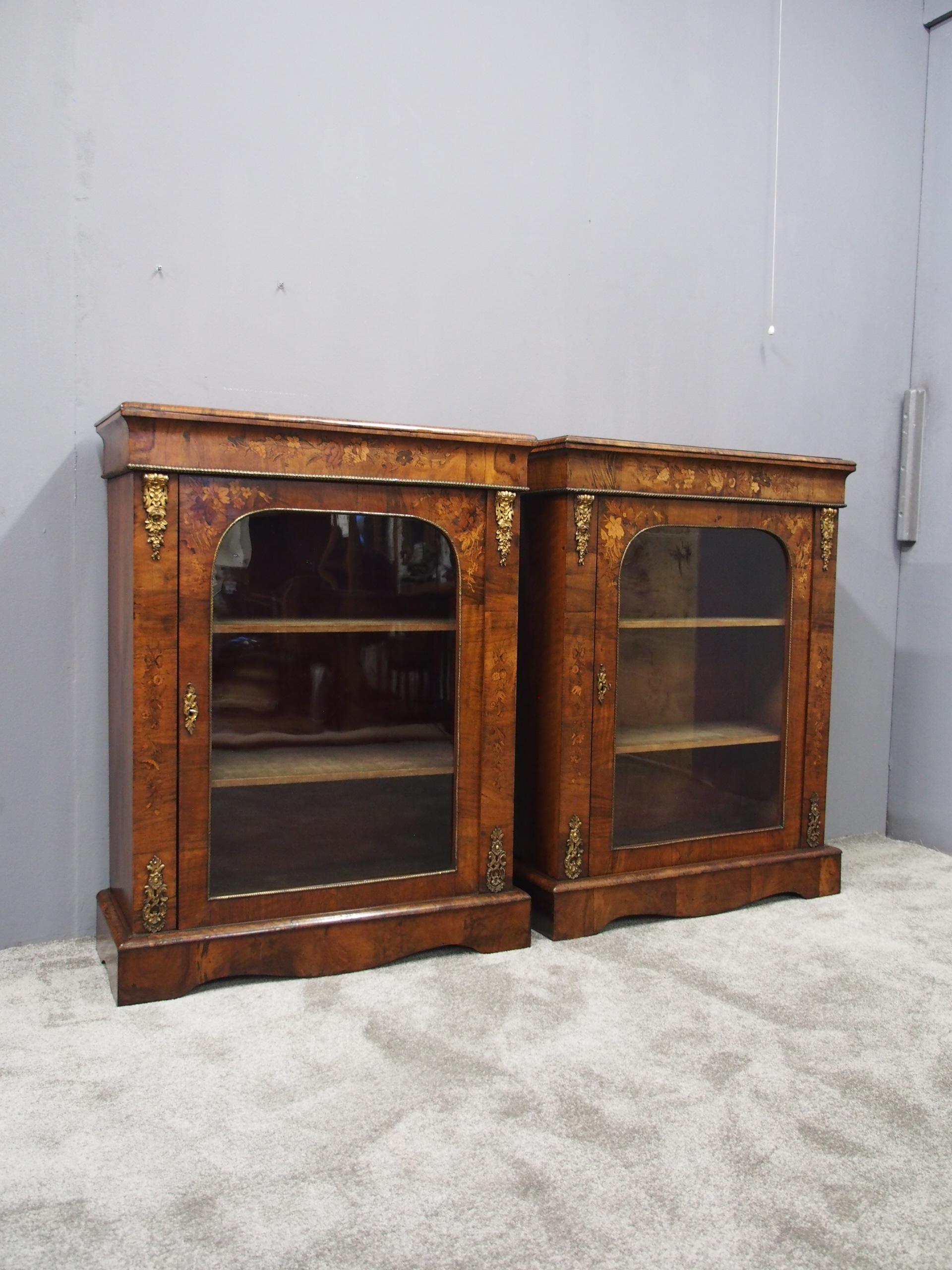 Pair of mid-19th century marquetry inlaid walnut pier cabinets, circa 1870. The rectangular tops in figured walnut with moulded edges over an ormolu-mounted frieze with floral marquetry decoration. The inlaid and ormolu-mounted arched doors open to