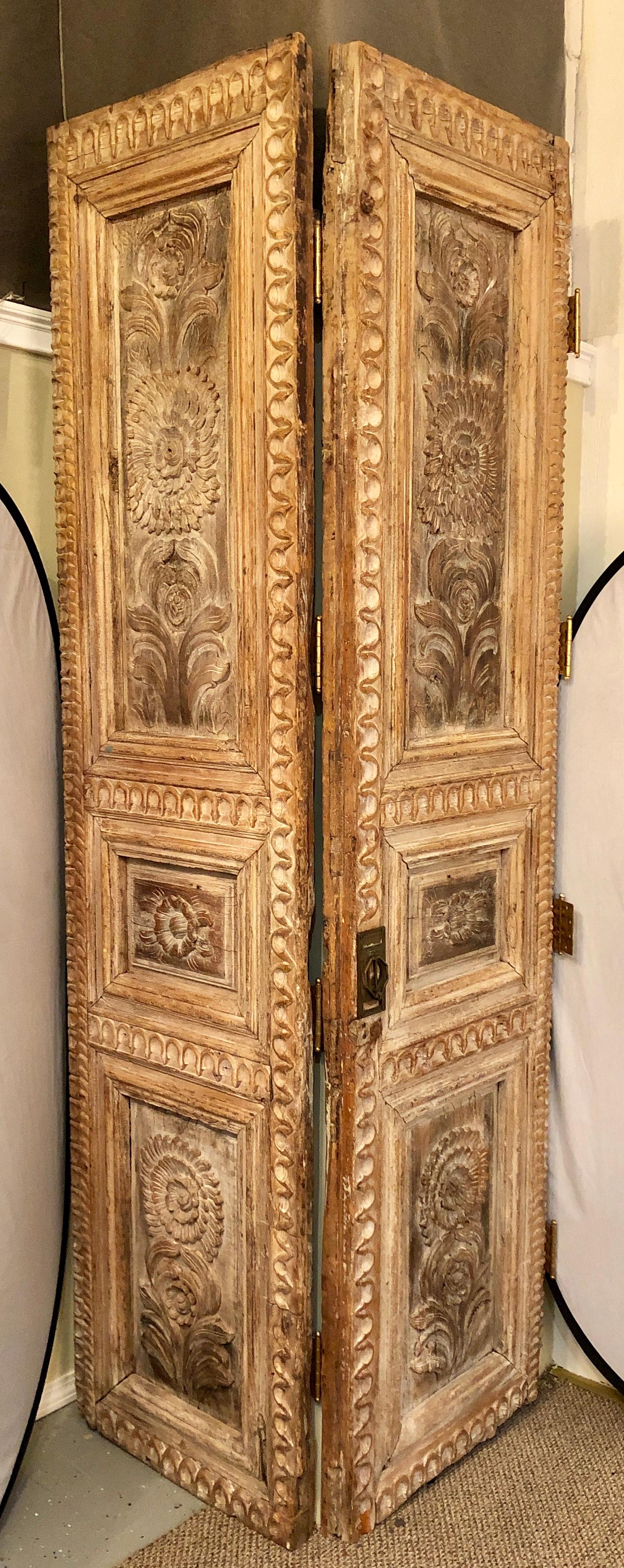 Pair of monumental Folk Art doorways mounted as room dividers. These large and impressive very fine carved doors are hinged together and can easily come apart to be used as their intended purpose or as room dividers. Each door having six panels of