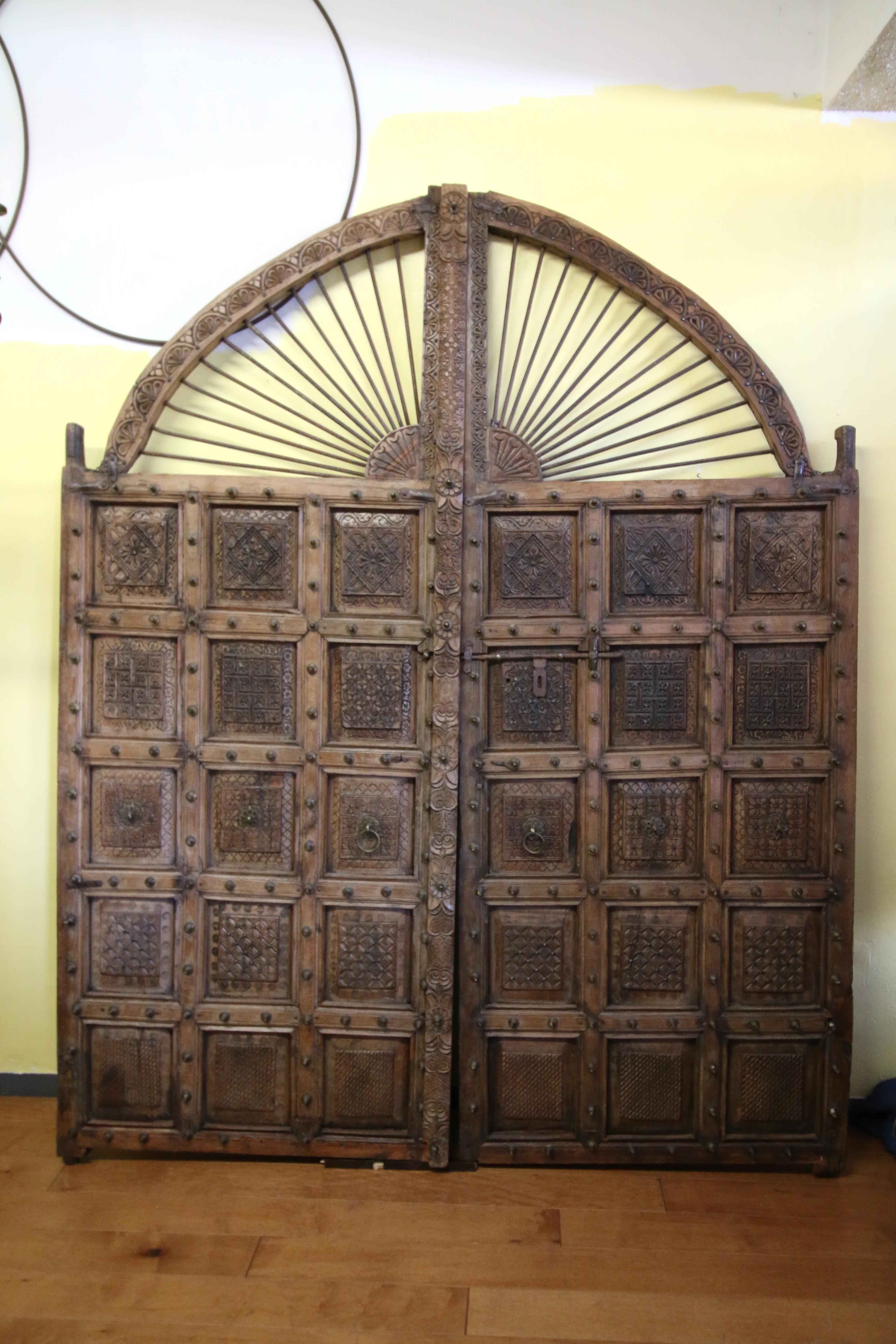 Impressionanti porte indiane antiche intagliate a due ante, realizzate in legno massiccio e metallo con intricati dettagli in bronzo. Un legno intagliato assolutamente straordinario. Può essere utilizzato come cancello da giardino o come elemento