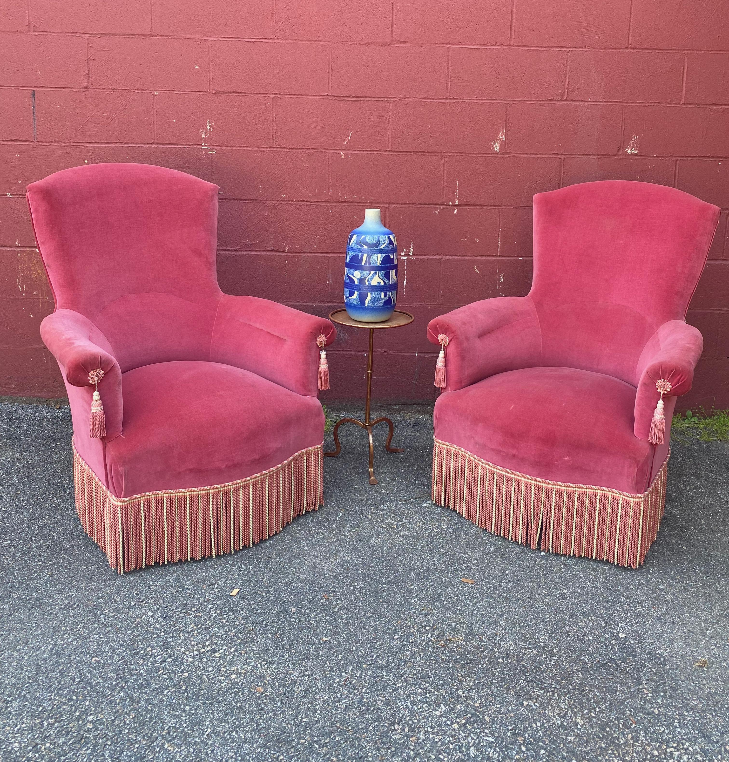 Wonderfully proportioned pair of French Napoleon III armchairs. Upholstered in vintage raspberry colored velvet with contrasting bullion fringe and tassels.

Sold in good vintage condition, as is.