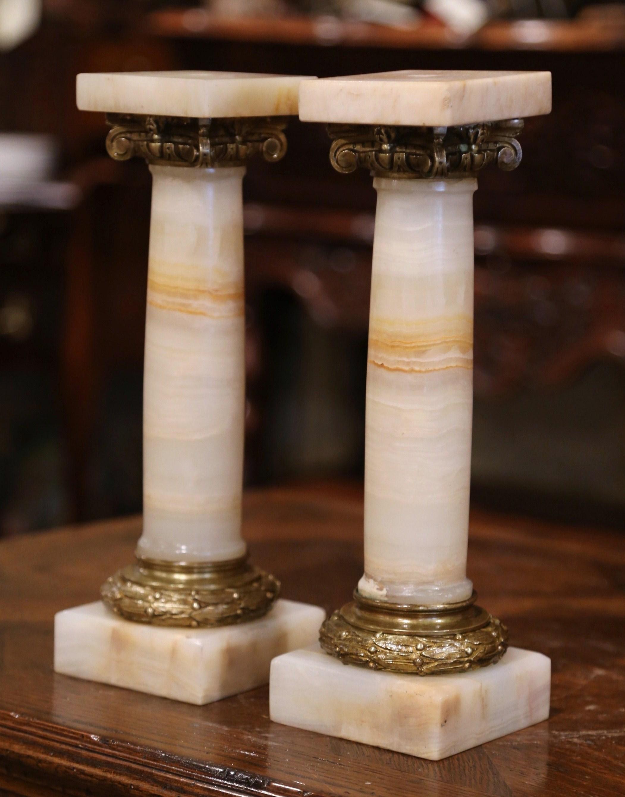 Turn these antique columns into table lamps or use them as decorative candle holders. Crafted in France circa 1870, each column sits on a square base and features decorative bronze mounts around the carved beige marble post; each piece has a square