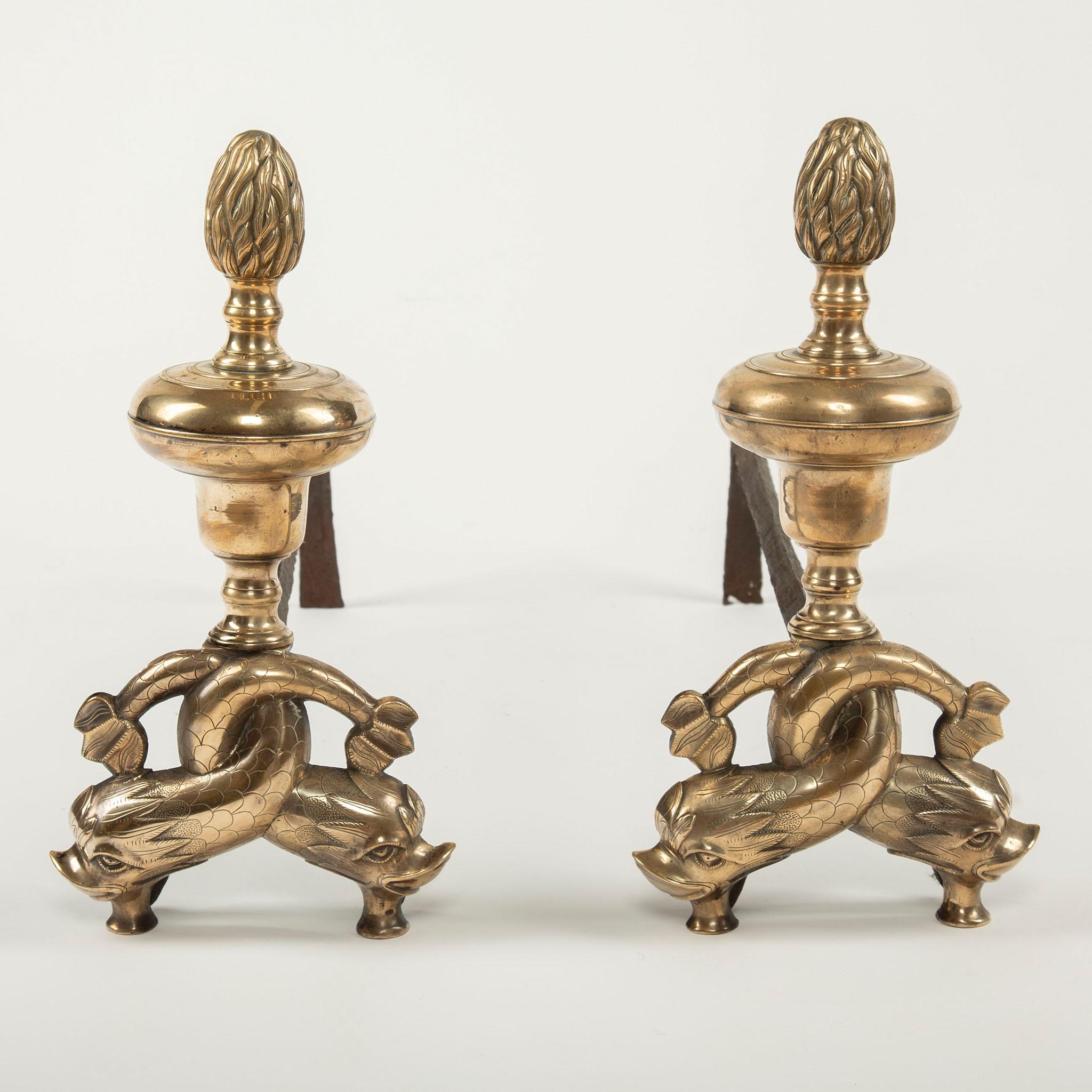 Pair of Early 19th Century Neoclassical Andirons with Interlocking Dolphin Motif
A finely cast pair of early 19th century gilt-bronze and wrought iron andirons, each featuring an elegant neoclassical design surmounted by an acorn finial above boldly