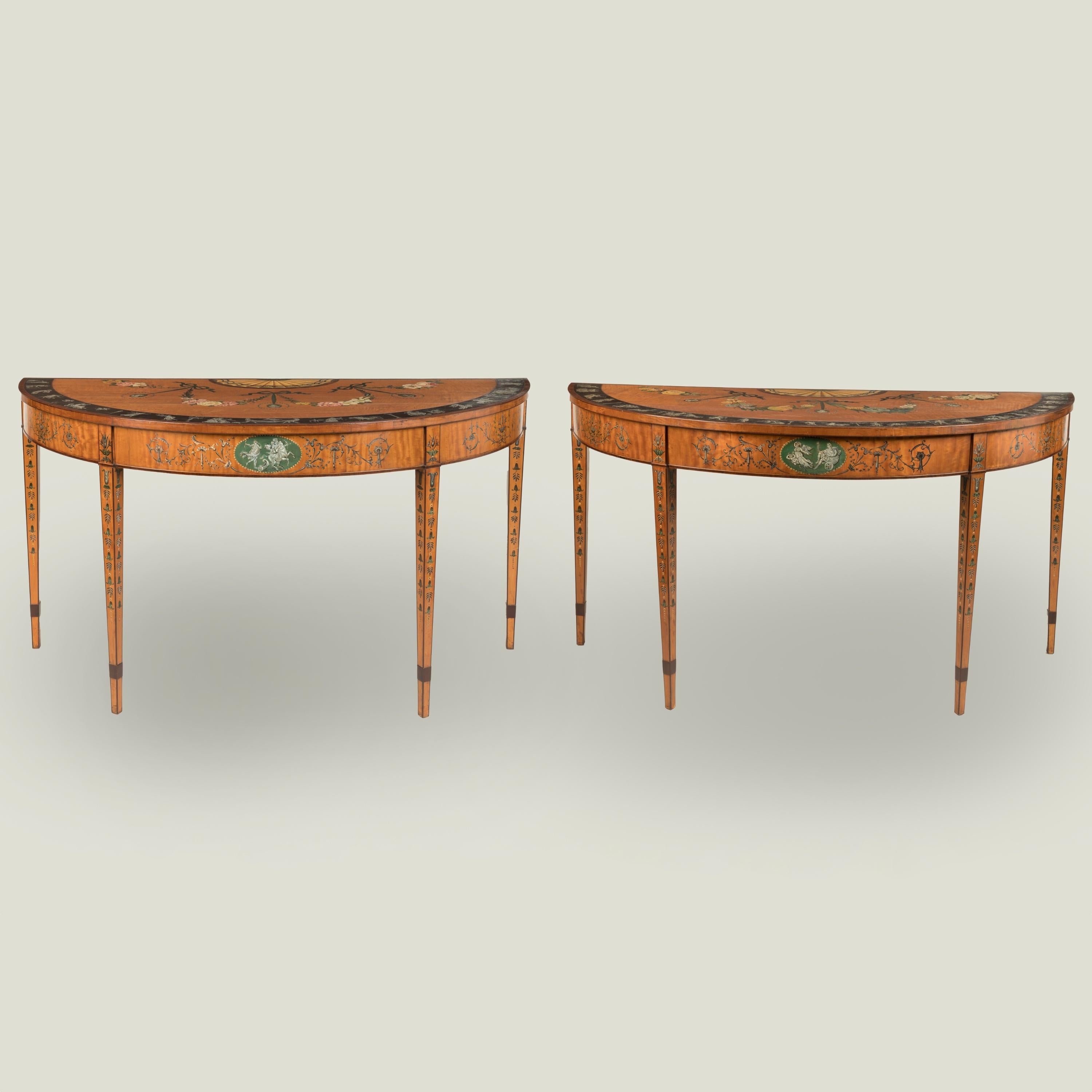 A Fine Pair of Neoclassical Painted Satinwood Console Tables

Of demilune outline, veneered with satinwood and decorated with polychrome paintwork; each table supported on four square tapering legs adorned with painted bellflowers and anthemia; the