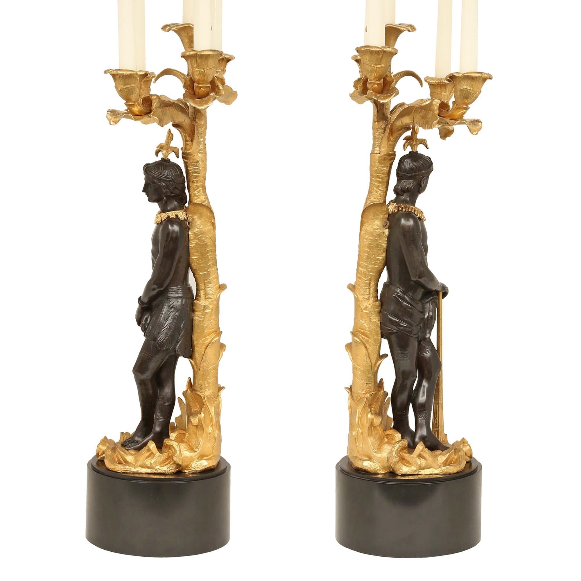 A wonderful and true pair of French 19th century Neo-Classical st. patinated bronze, ormolu and marble five arm candelabras. Each candelabra is raised by a thick, circular Black Belgian marble base with a mottled border. Above each are richly