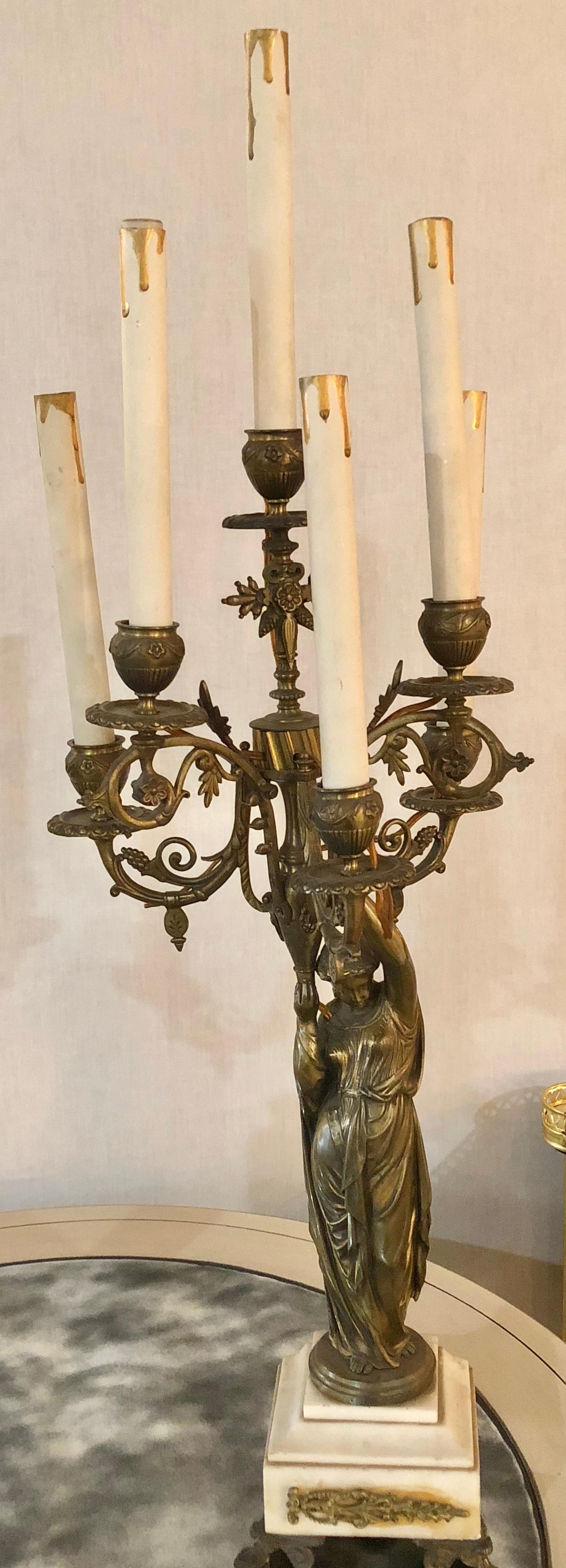 A pair of 19th century neoclassical style figural bronze candelabras, each having a full bodied woman supporting a five arm candelabrum. The whole on a marble and bronze base.