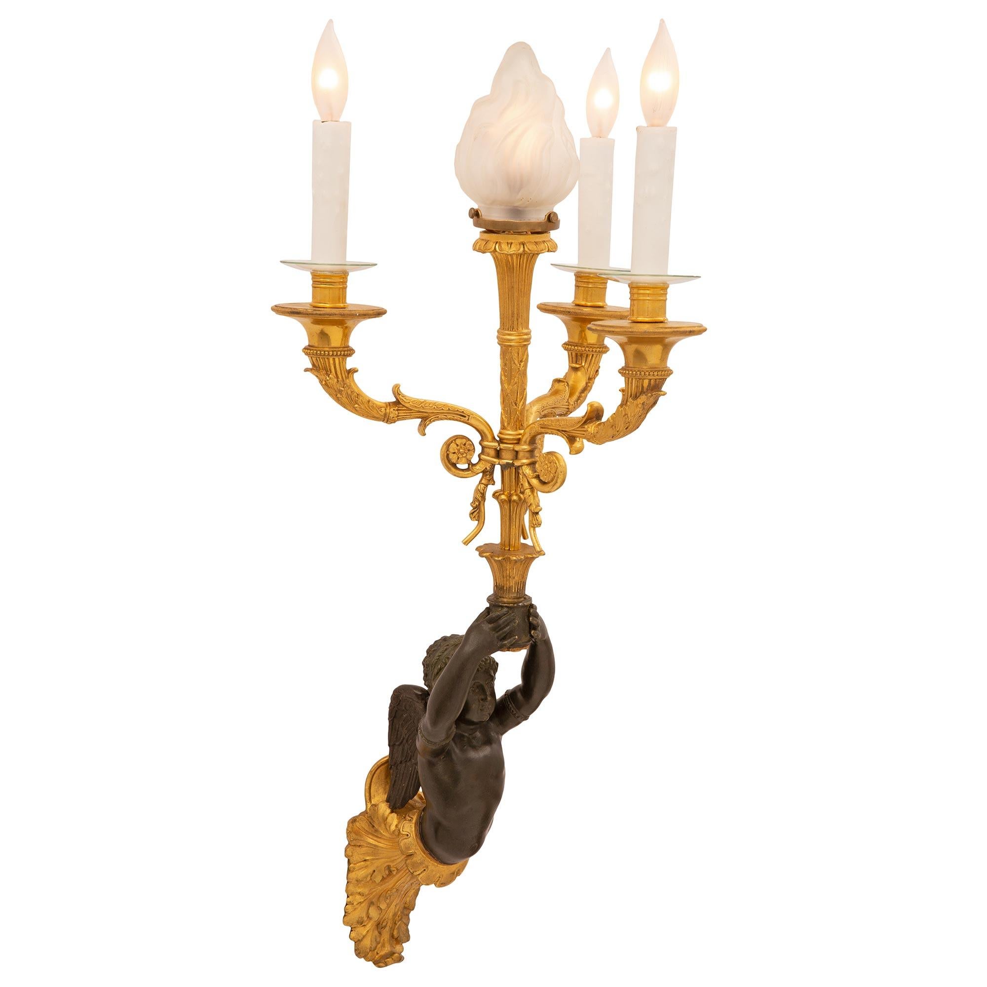 An outstanding pair of French 19th century Neo-Classical st. patinated bronze and ormolu sconces. Each four arm sconce is centered by a richly chased ormolu acanthus leaf backplate from where the charming and finely detailed patinated bronze cherubs
