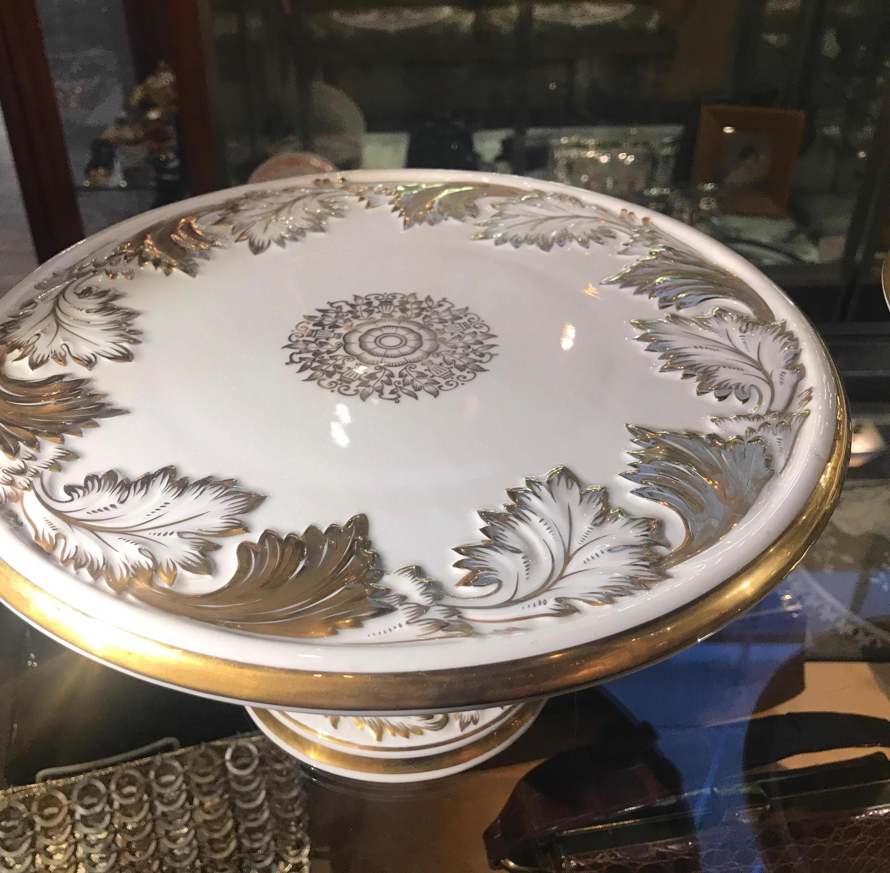 A pair of 19th century Nymphenburg porcelain and gilt pedestal compote cake stands. The white porcelain background with raised leaf decoration hand gilt on the edges. The blue shield mark, under-glaze is from the 1890s
The Nymphenburg porcelain