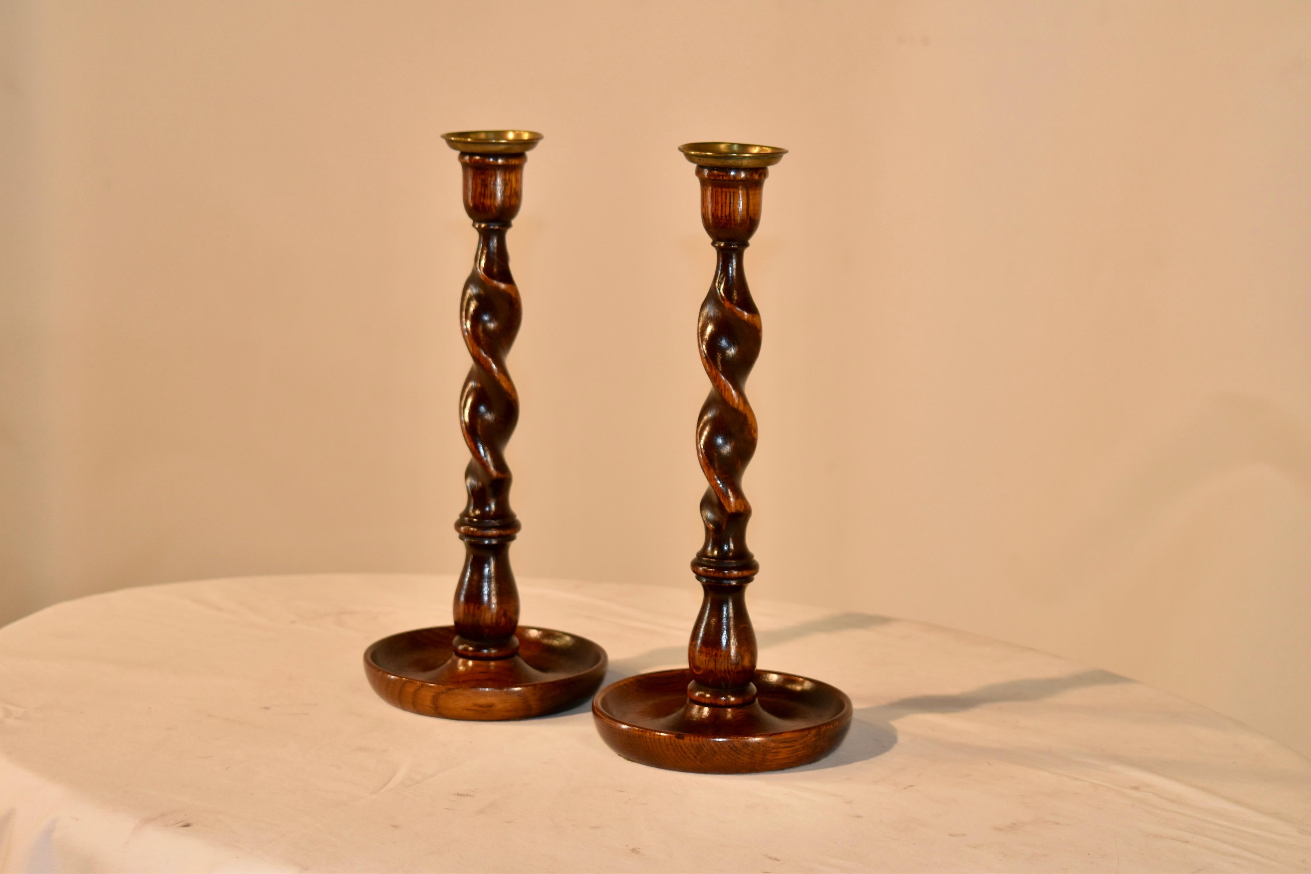 Pair of 19th century oak candlesticks from England with hand turned brass candle cups, supported on hand turned candle cups and barley twist stems, sitting on a hand turned dish shaped base.