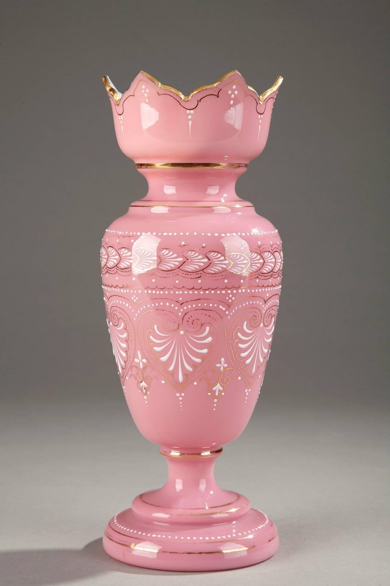 Pair of baluster-shaped, pink opaline vases with wide, petal-shaped openings. They are decorated with white enamel palmettes, small dots, and floral motifs. Gold bands accent the enamel as well as the neck, paunch, and base of each vase. Very