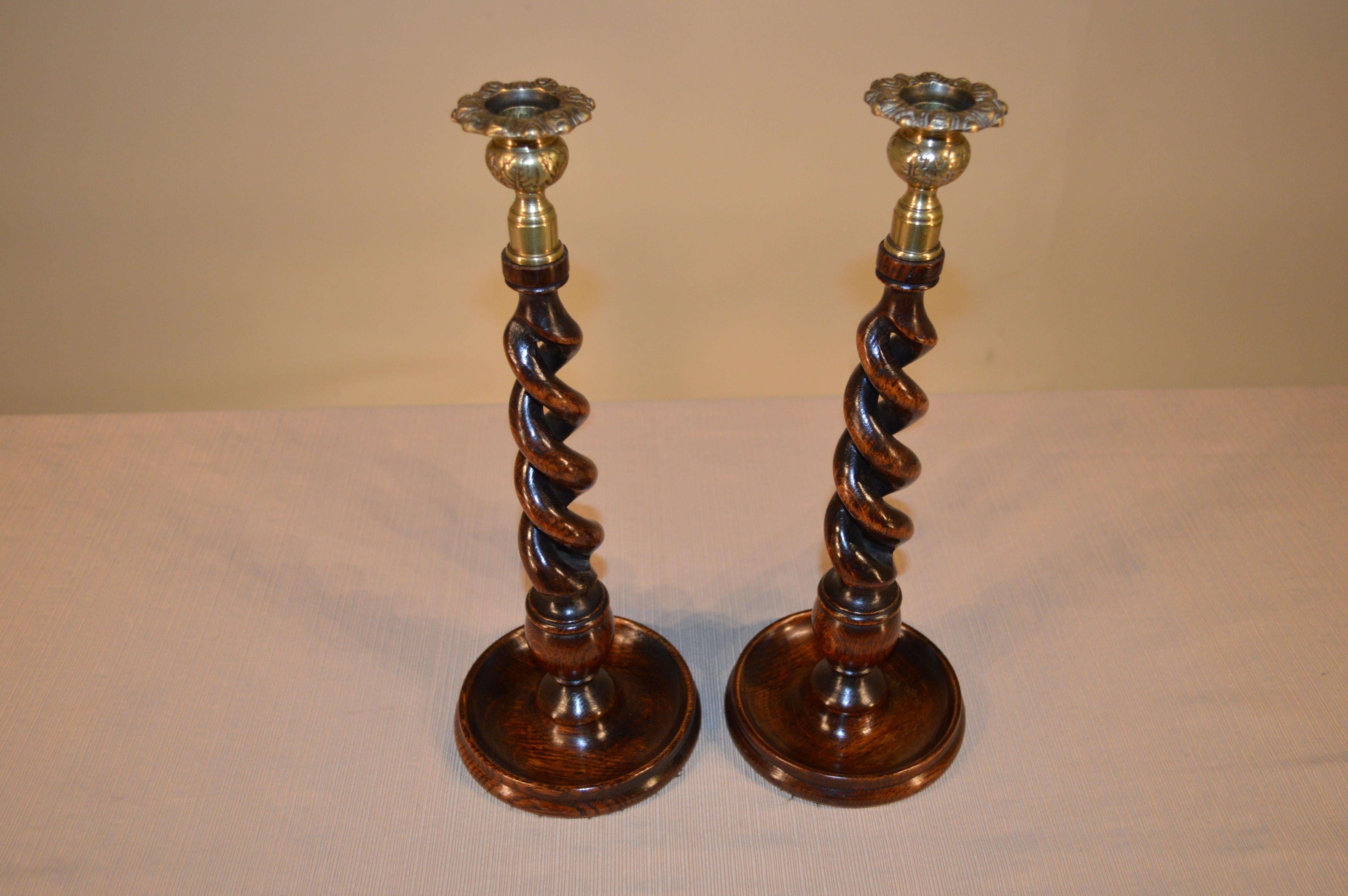 Late 19th century English oak candlesticks with hand-cast brass candle cups and hand-turned open barley twist stems, resting on hand-turned dish bases.