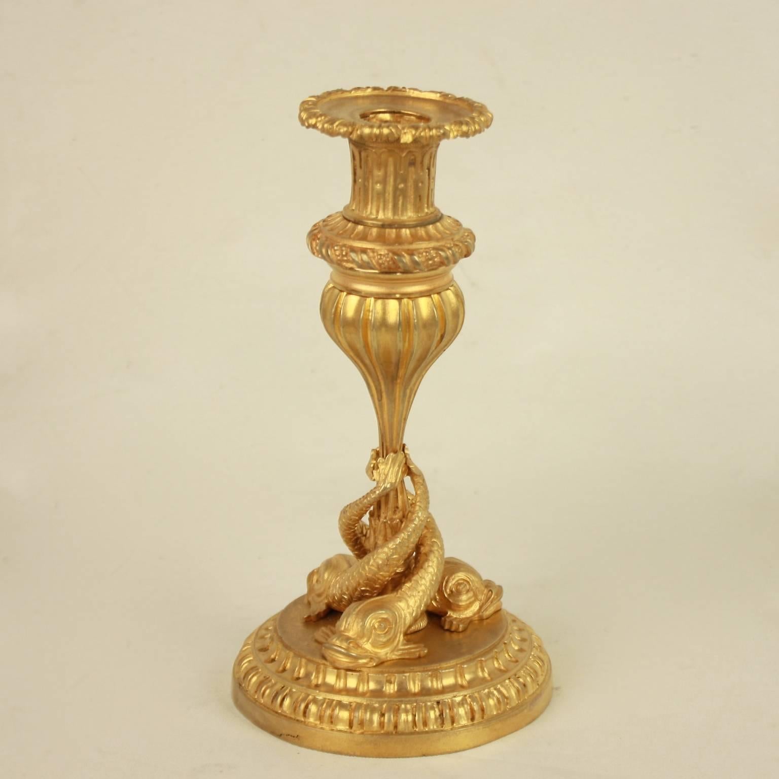 A fine pair of Louis XVI style ormolu candlesticks with entwined dolphins. Three entwined finely chased dolphins forming the shaft above a fluted circular base. The socket and drib plates similarily fluted as the base with a twisted ribbon motif.