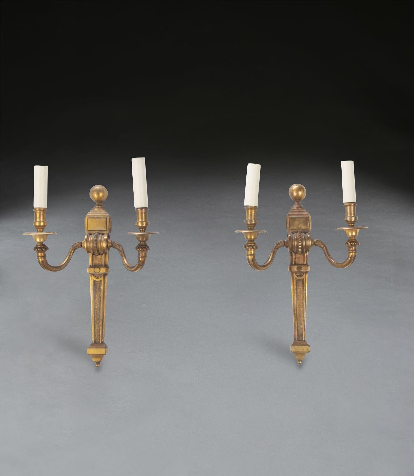 A classical pair of 19th Century ormolu wall lights, the scroll twin branches with tapering pilaster bodies. Circa 1840. In good condition with no twists to the scones or damage. Lamp holders can be adjusted to be straight.

H: 40 cm (15 3/4