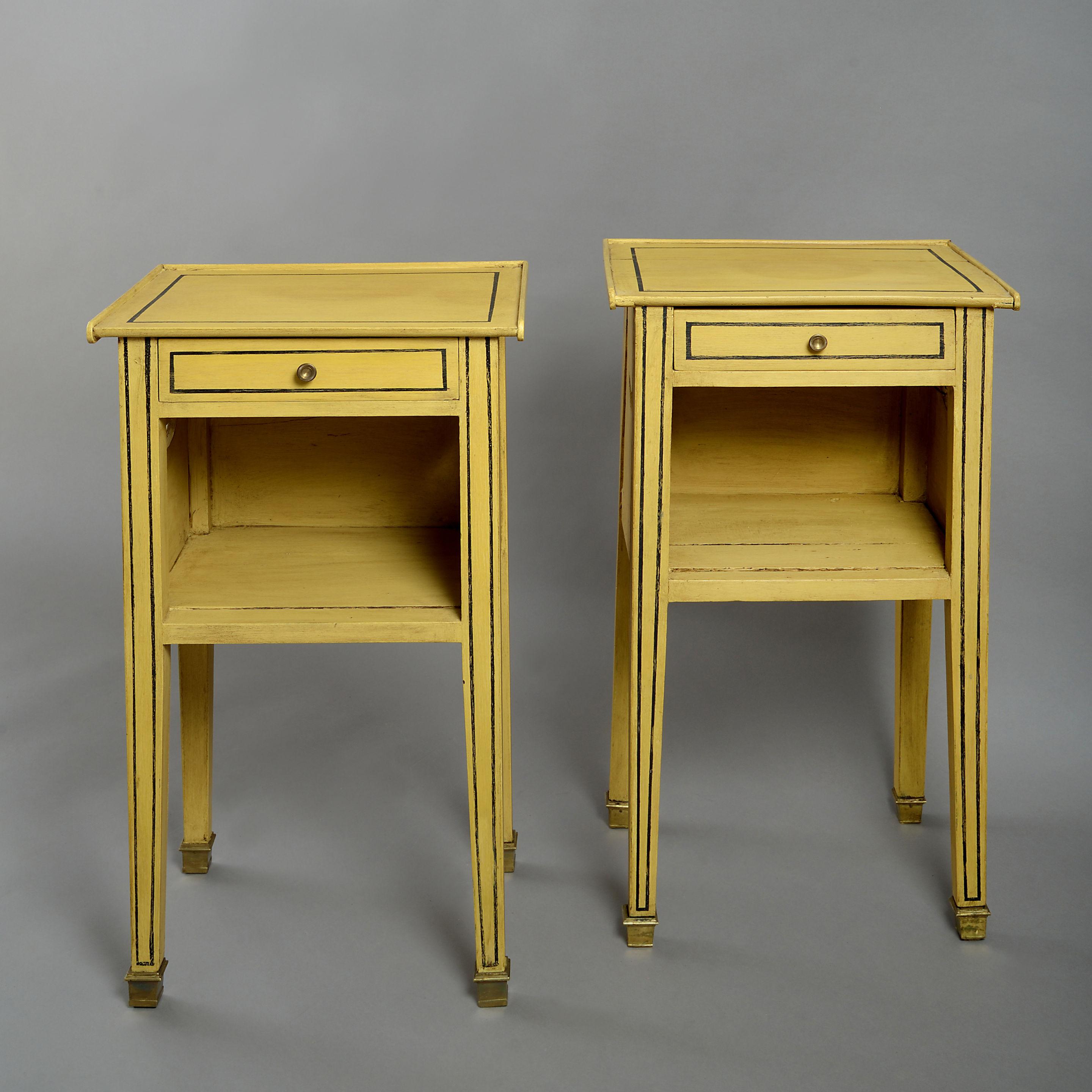 A pair of 19th century ochre and black painted bedside tables in the Directoire manner, each having a single drawer above an opening and raised on square tapering legs with brass capped feet.