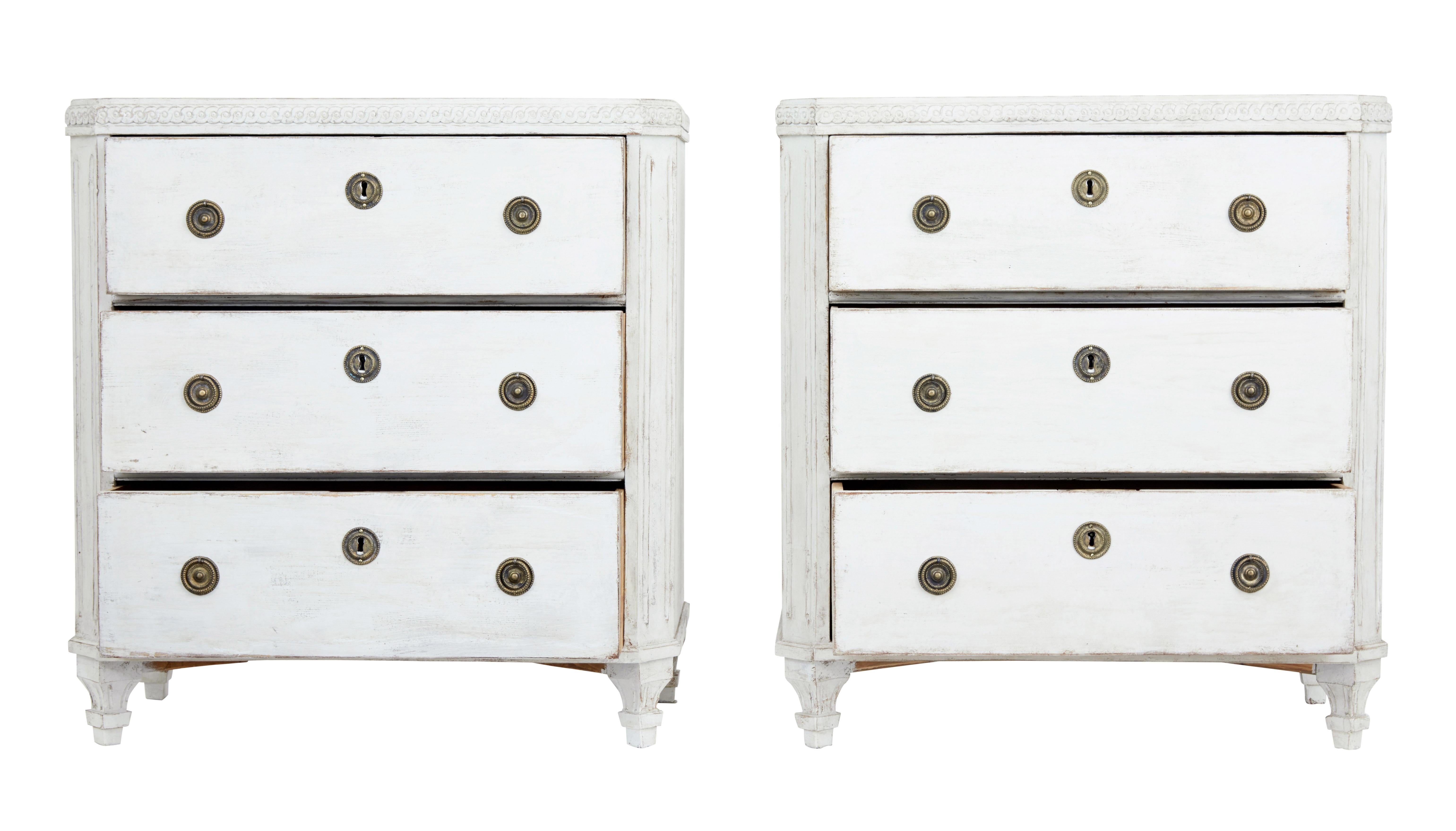 Pair of painted Swedish commodes, circa 1880.

Carved scrolling detail the top surface. Canted corners with fluted detail. 3 drawers with brass ring handles and escutheons.

Standing on detailed tapered legs.

Later paint and hardware,