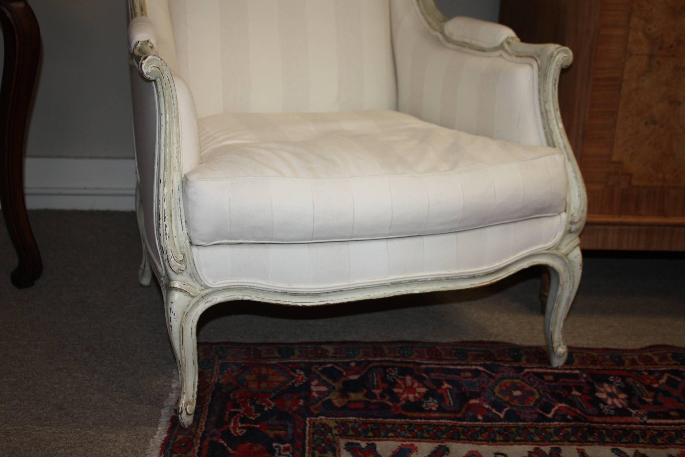 This is a great looking pair of painted French bergeres recently upholstered in a two tone striped fabric. The patina is very nice. The legs are Louis XVI style. The carvings on the chair are very attractive.