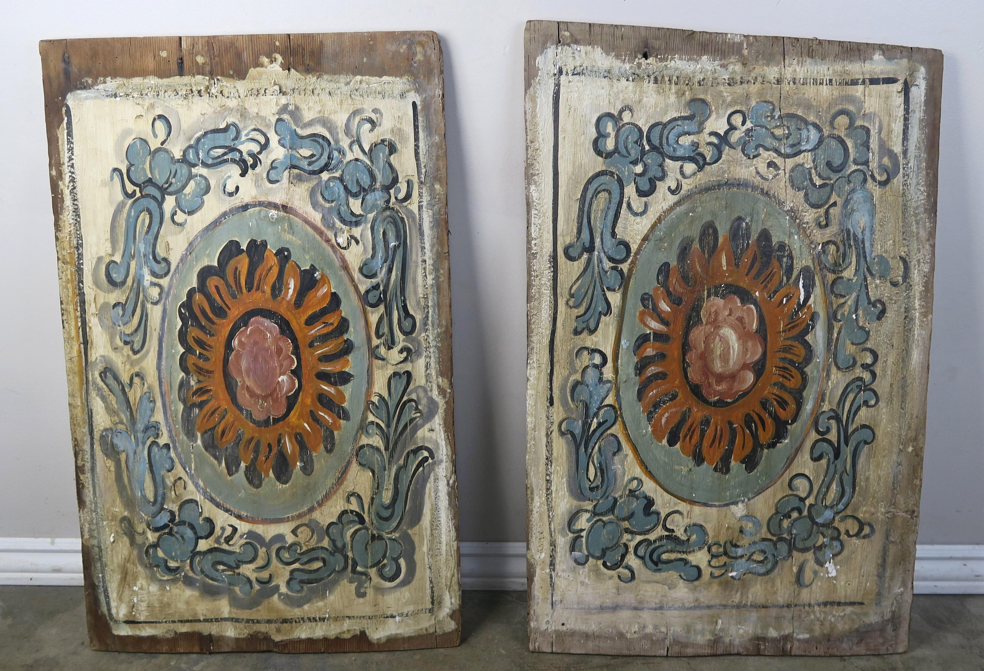 Pair of 19th century painted Italian panels depicting vibrantly colored rosette shaped flowers surrounded by blue painted scrolled and flower designs throughout.
